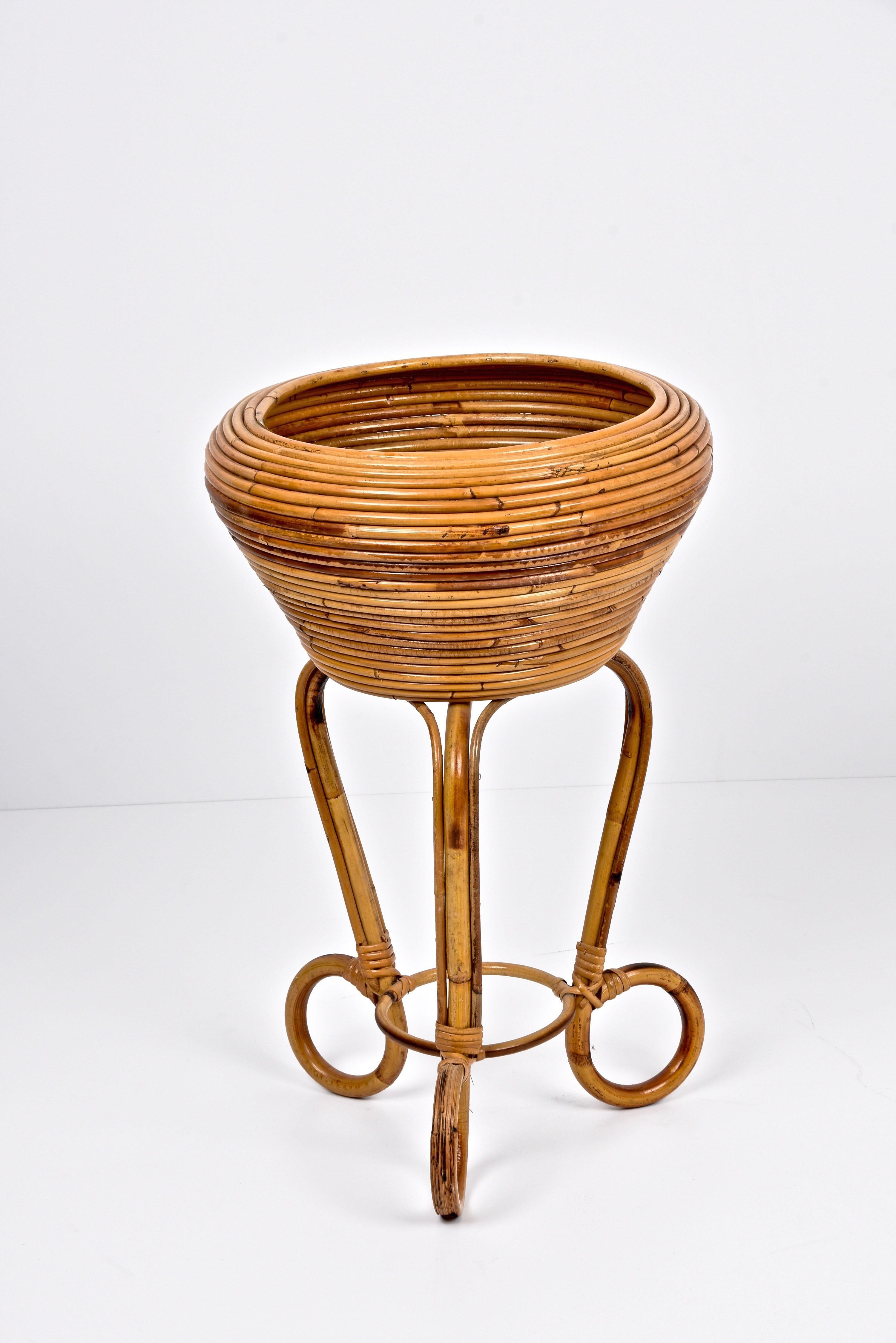 Amazing midcentury French Riviera round bamboo and rattan planter. This wonderful piece was designed in Italy during the 1960s.

This piece is amazing as the rattan body of the planter is made of concentric and round rattan, while the feet are