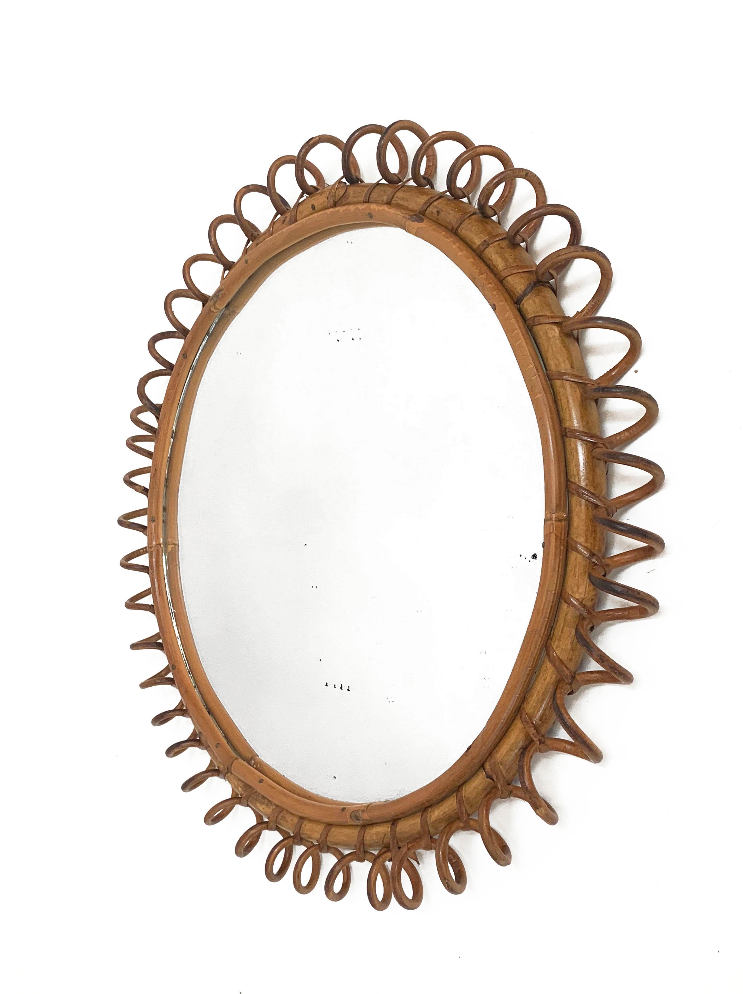 Amazing midcentury round rattan wall mirror. This Mid-Century Modern mirror was produced during the 1970s in Italy.

This wall mirror features a round mirror glass framed by a round bamboo cane and a rattan star shaped frame.

Beautiful placed