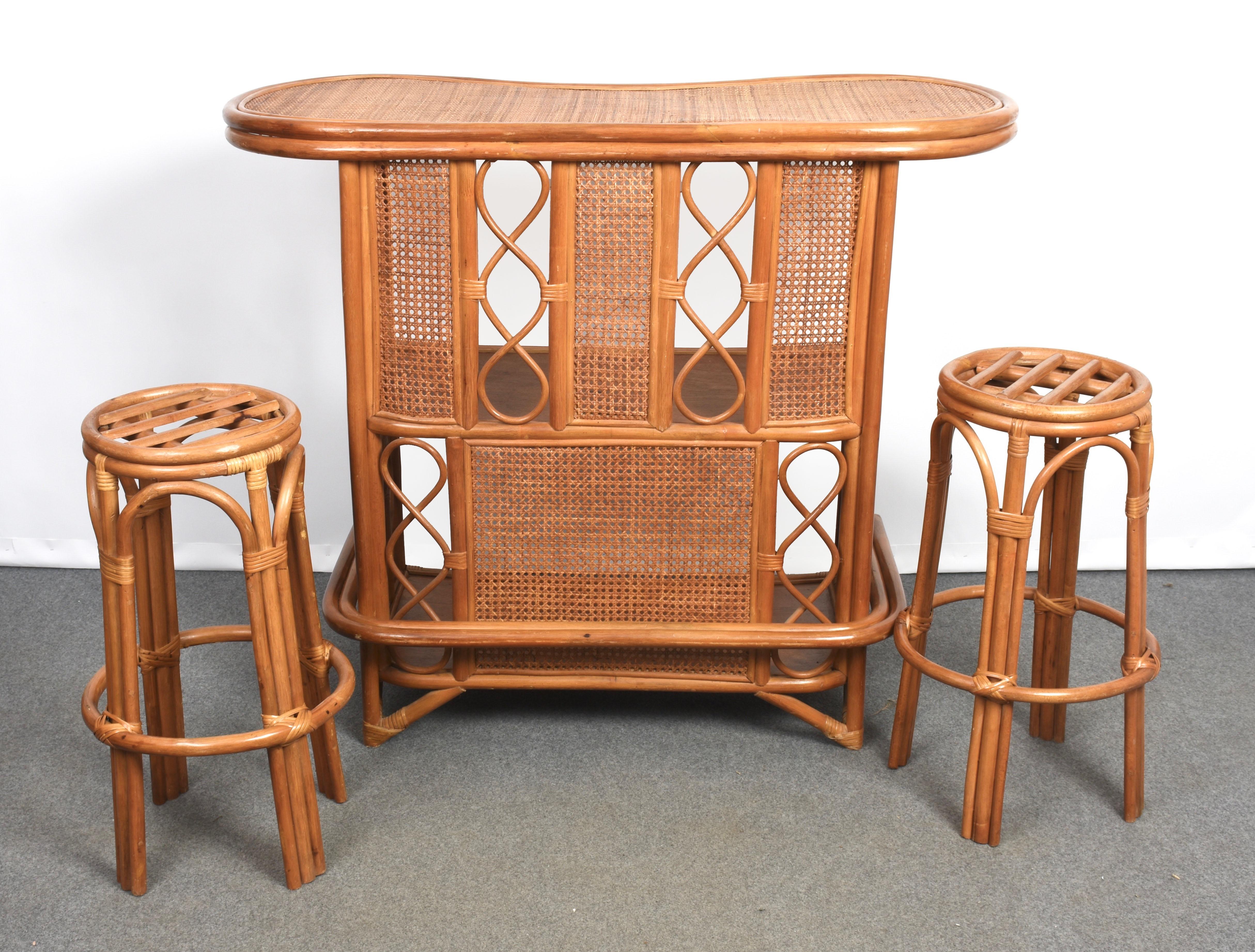 Amazing midcentury Wien rattan dry bar with two stools with double arch support. This spectacular set was produced in Italy during the 1960s.

This bar counter has two internal wooden shelves, is in good vintage conditions. Pillows are not