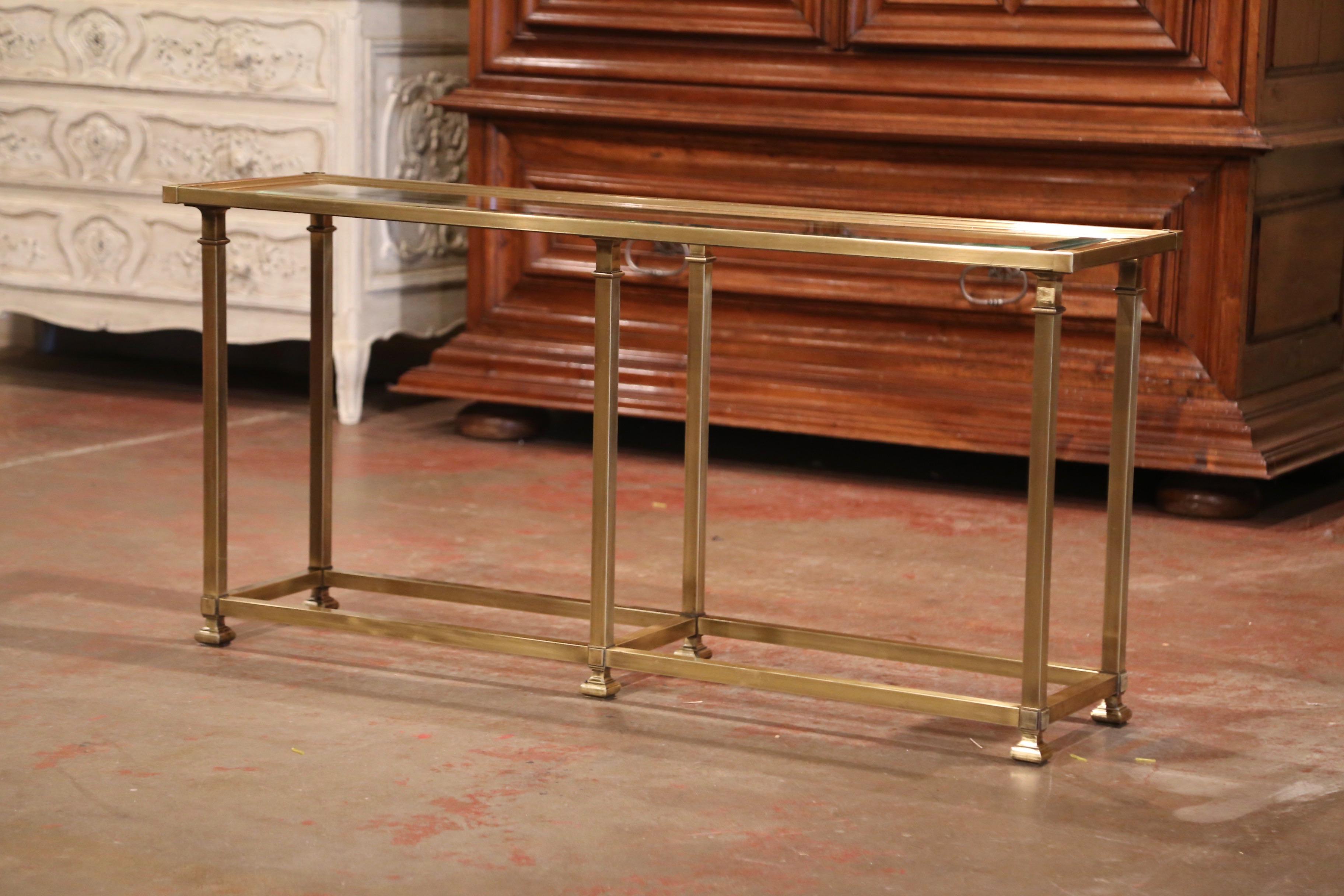This vintage console was created in France circa 1960; made of brass, and attributed to Maison Jansen in Paris, the table stands on six square legs embellished with bottom stretcher, and dressed with small feet at the base; the surface features an