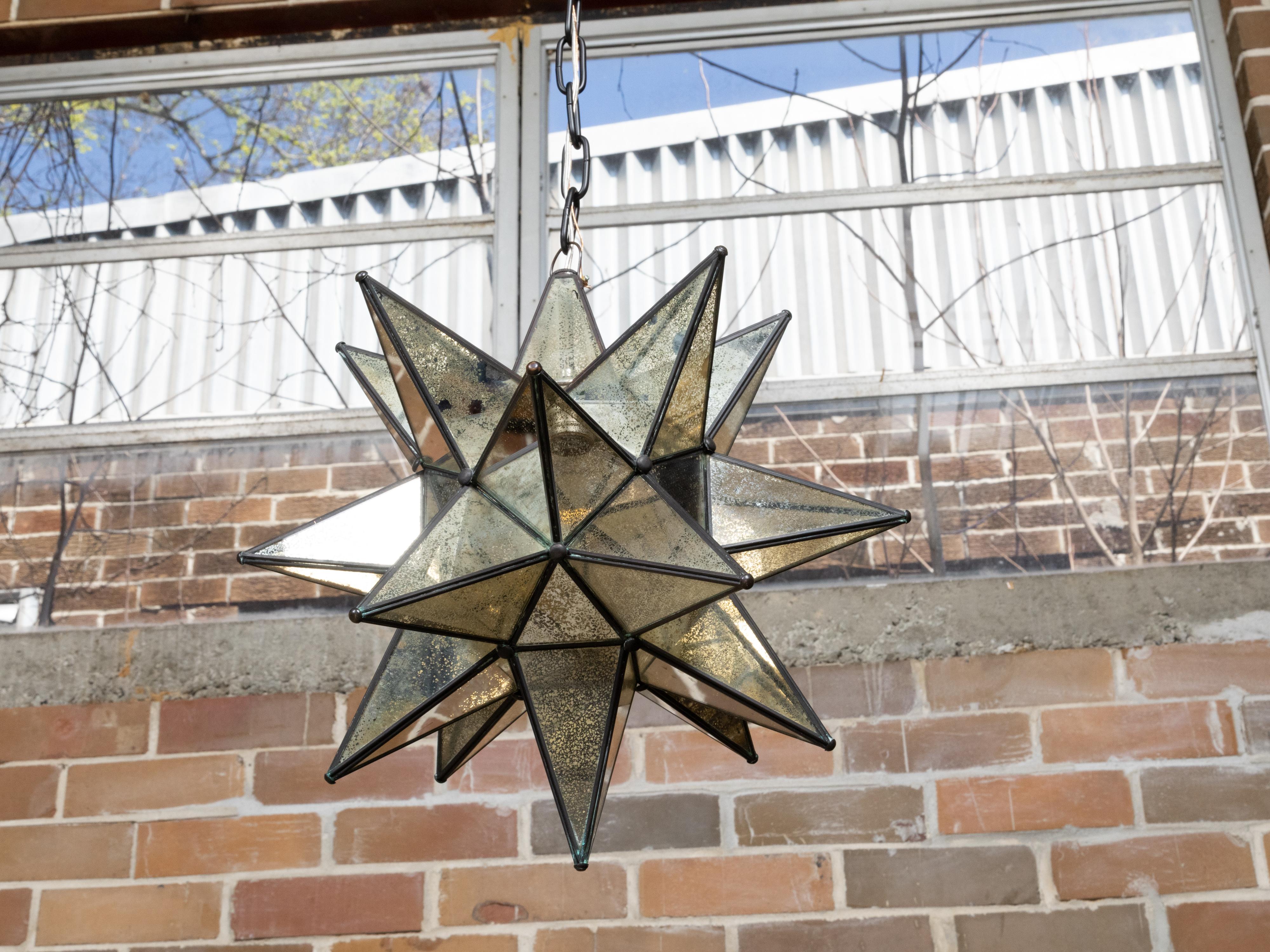 A small French star shaped light fixture from the Midcentury period, with antiqued mirrored panels and single socket. This French Midcentury star-shaped light fixture brings a celestial touch to any interior with its antiqued mirrored panels and