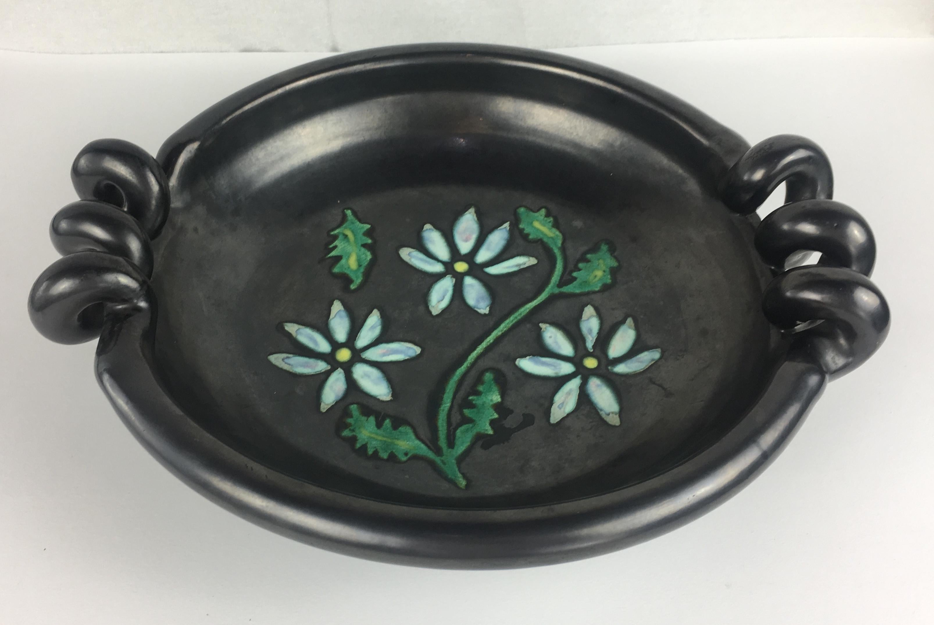 Midcentury sculptural bowl with a very nice black matte finish with floral design in the center and rope style handles. Signed.

This interesting semi-glazed piece will look good on any coffee table or countertop. It can also be used as a fruit