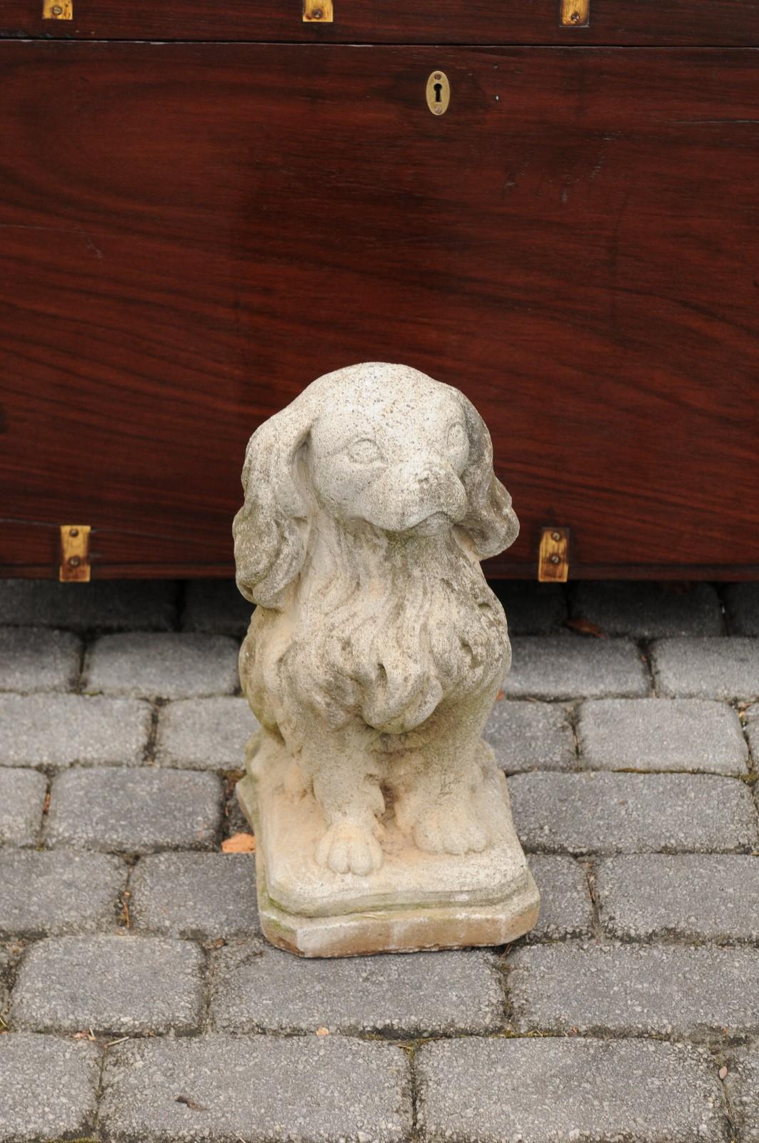 A French vintage carved stone dog sculpture from the mid-20th century with nicely weathered patina. Born in France in the midcentury, this charming dog statue steals our hearts with its air of innocence. The Spaniel dog is sitting obediently on a