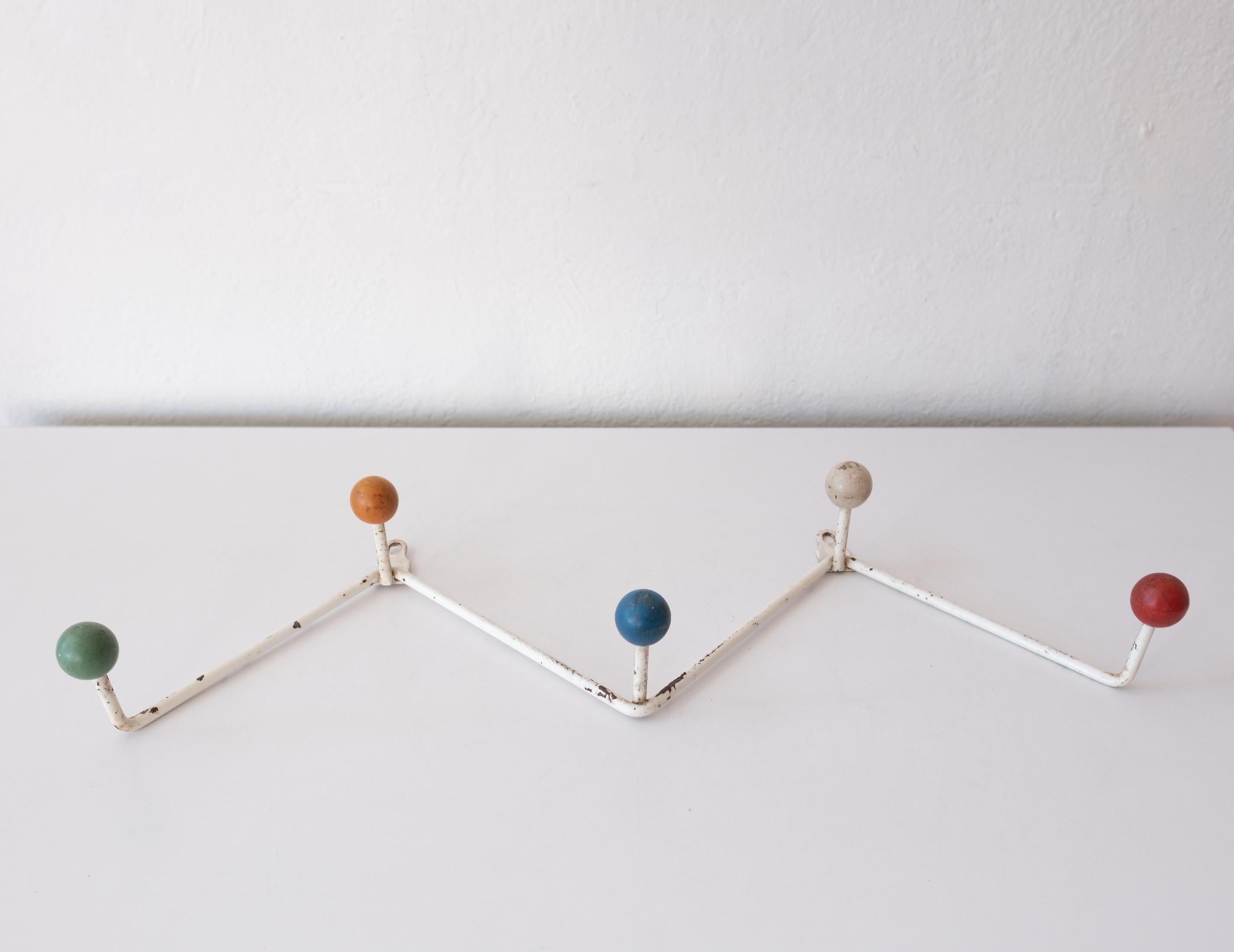 Wall mounted hat or coat rack from France. Solid rod iron frame with wood balls. Original white paint with lovely patina. Two small brackets for screws allow for wall hanging. 1950s.