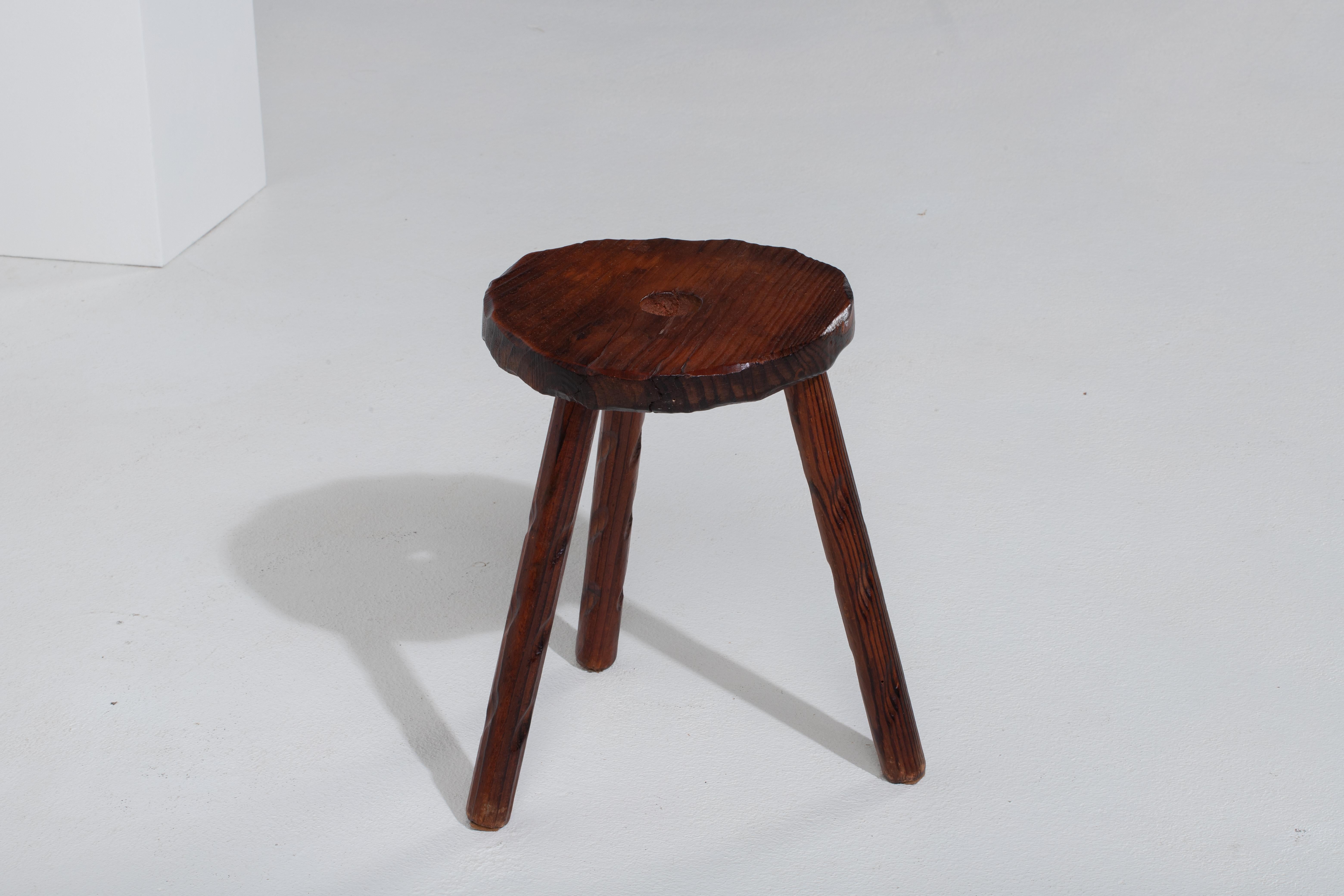 Introducing a fantastic midcentury wooden stool, crafted in France during the 1960s. This piece is constructed without the use of hardware, boasting an elegant round seat, flared legs, and intricate gouge work, all made from rich walnut.

The design