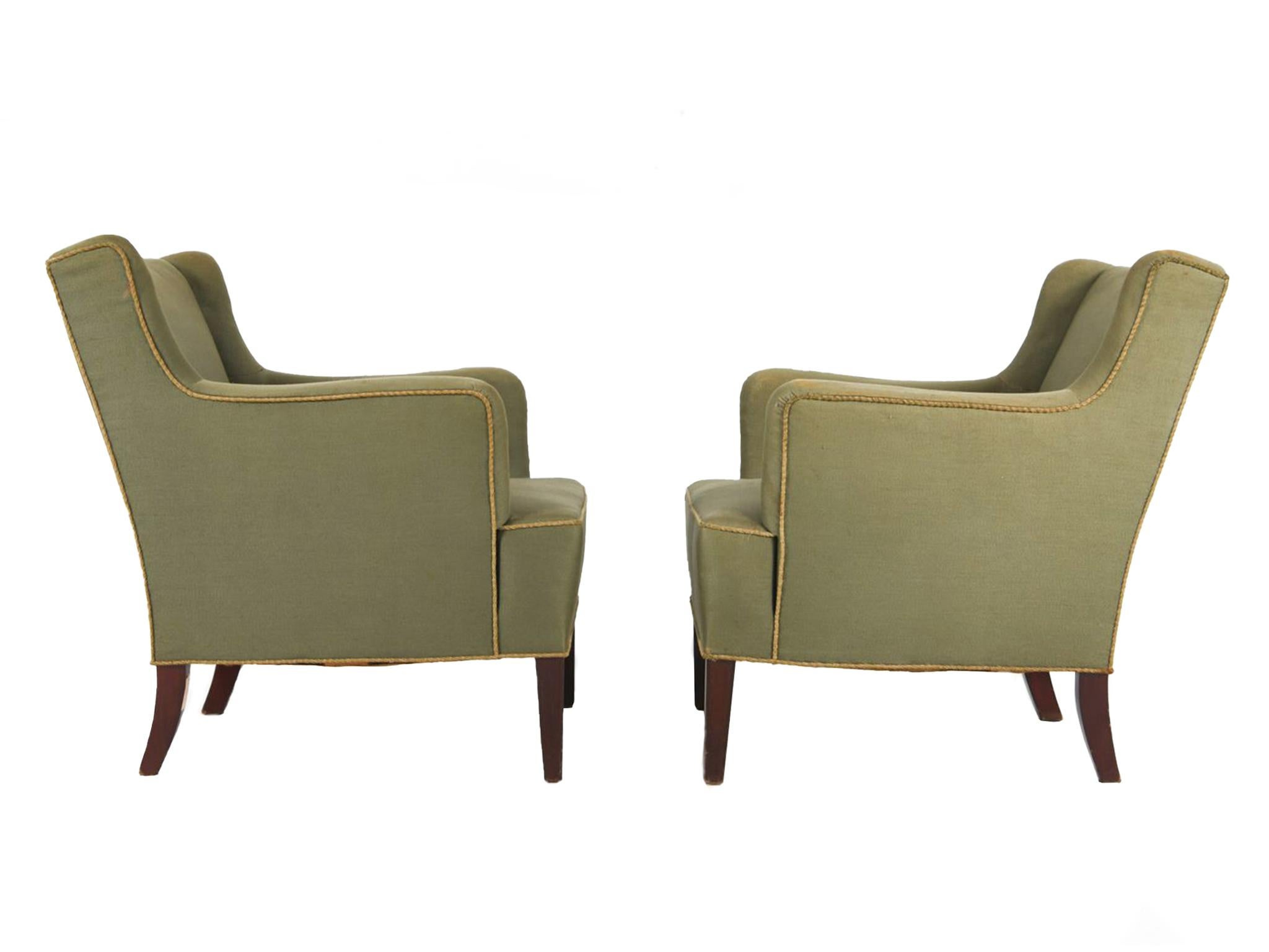 Diseñados por Frits Henningsen y fabricados en la década de 1950, estos sillones constan de armazón de caoba y tapicería de lana verde oliva con ribetes de cuerda amarillo pálido. El diseño de Henningsen es de líneas rectas y formas redondeadas,