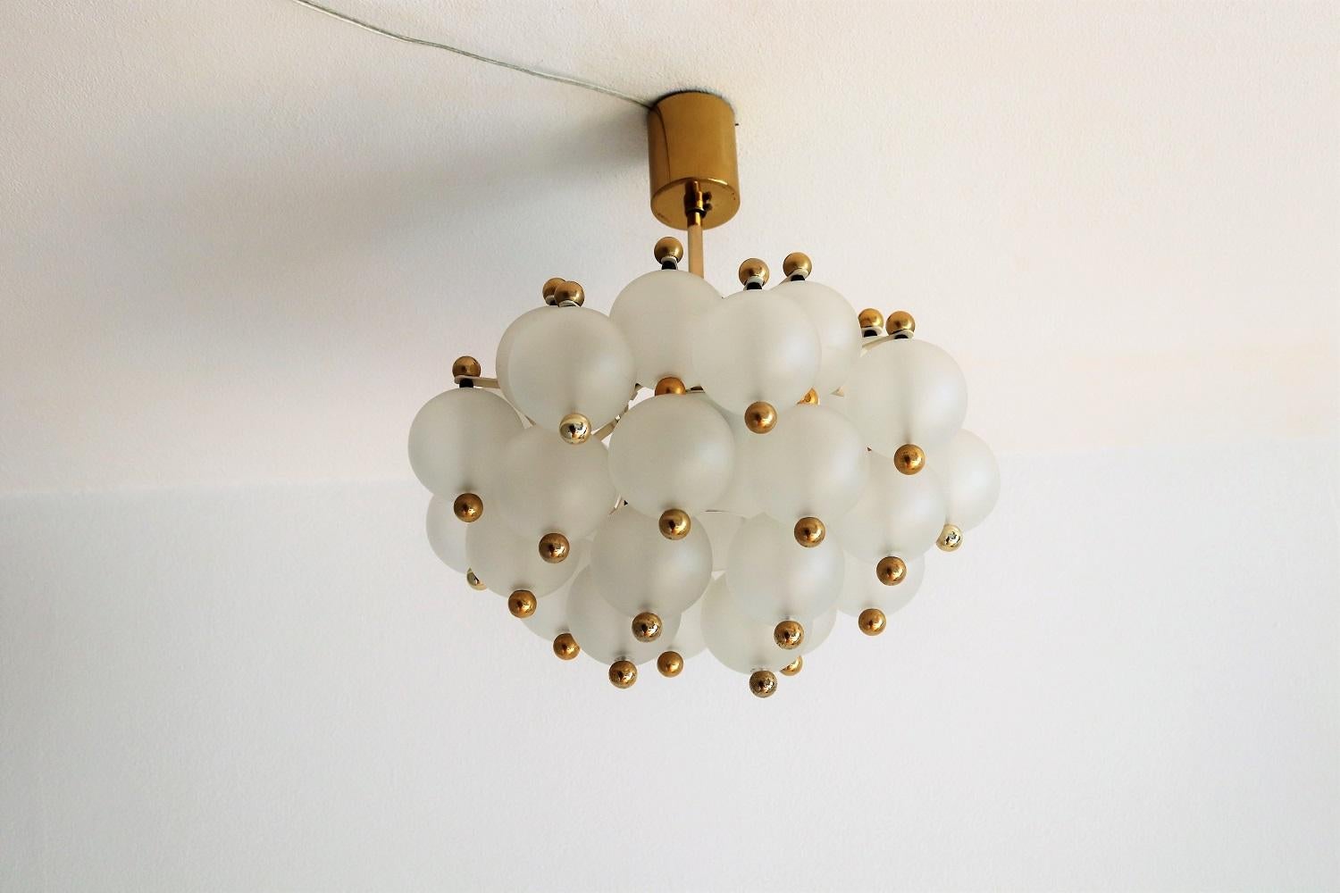 Beautiful complete chandelier with 31 frosted glass balls and one dome center glass, made in Germany in the 1970s by Kinkeldey.
The chandelier has a metal frame with brass bar to ceiling and brass ceiling rose. The golden smalls balls are varnished