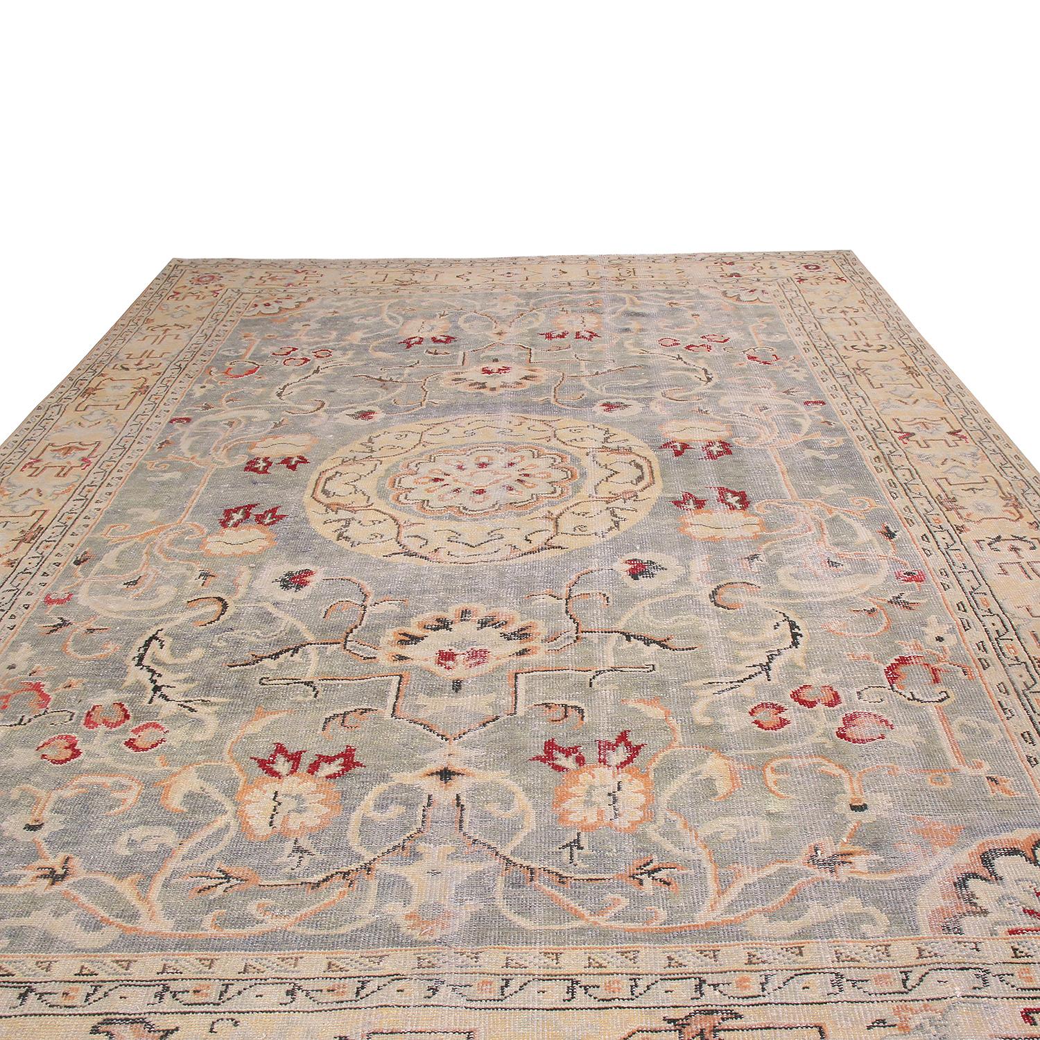 Hand knotted in Turkey with high-quality wool, this geometric rug enjoys minimal distress and a variety of inspirations from Khotan pieces, particularly in the Fine, elegant floral motifs perfectly mirrored throughout the abrashed blue field and