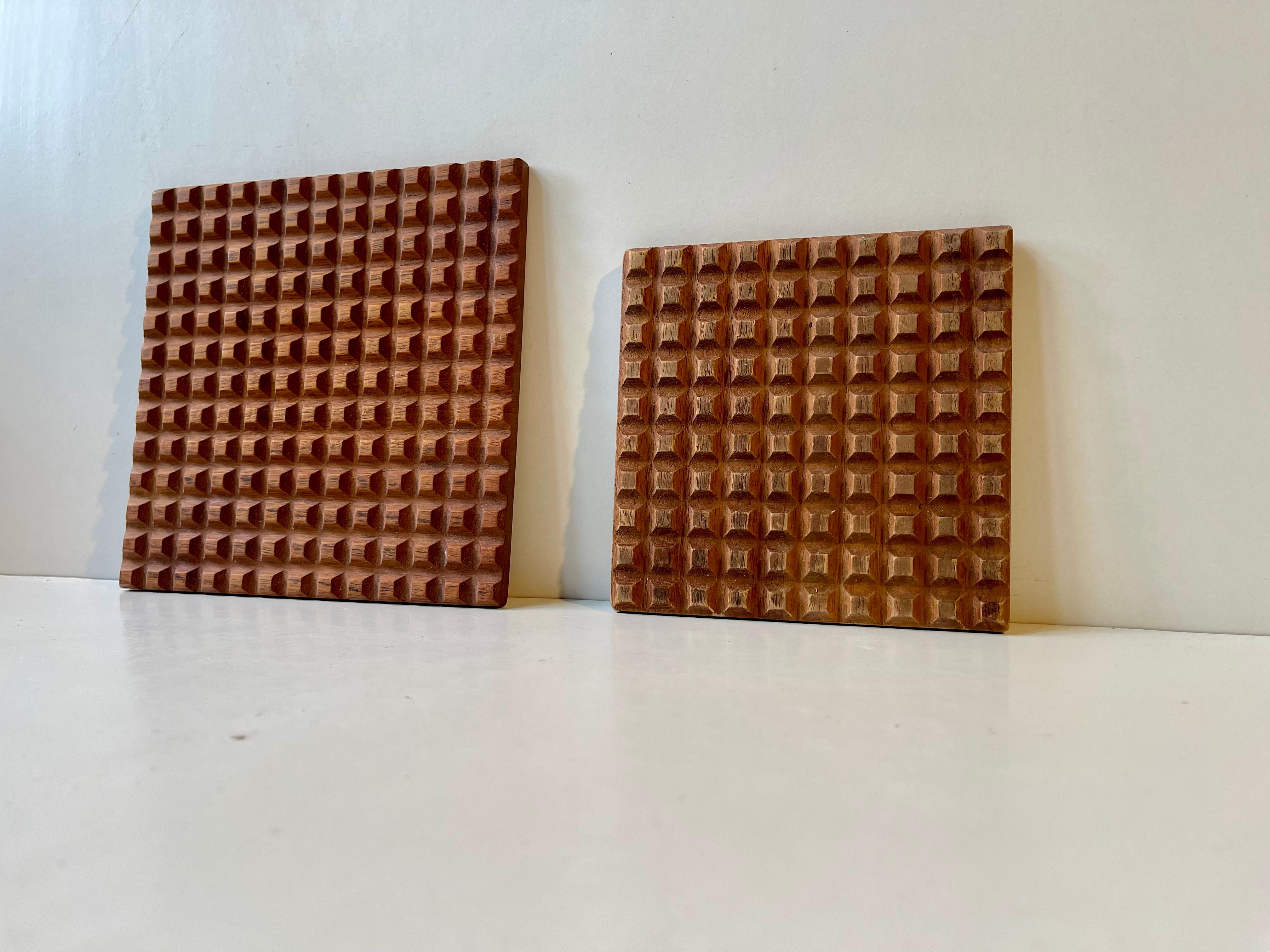 Ein Set von Untersetzern aus massivem Teakholz mit geometrischen Mustern, ähnlich der Ultimo-Serie von Bäckström & Ljungberg. Dieses Set mit den Maßen 18,5x18,5 cm und 14x14 cm wurde in den 1960er Jahren von Skjøde Skjern in Dänemark hergestellt.