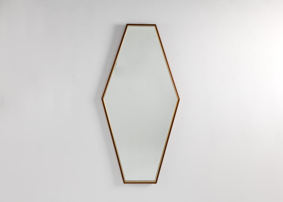 A pair of large midcentury mirrors in vertical hexagonal shapes framed in thin borders of painted wood.