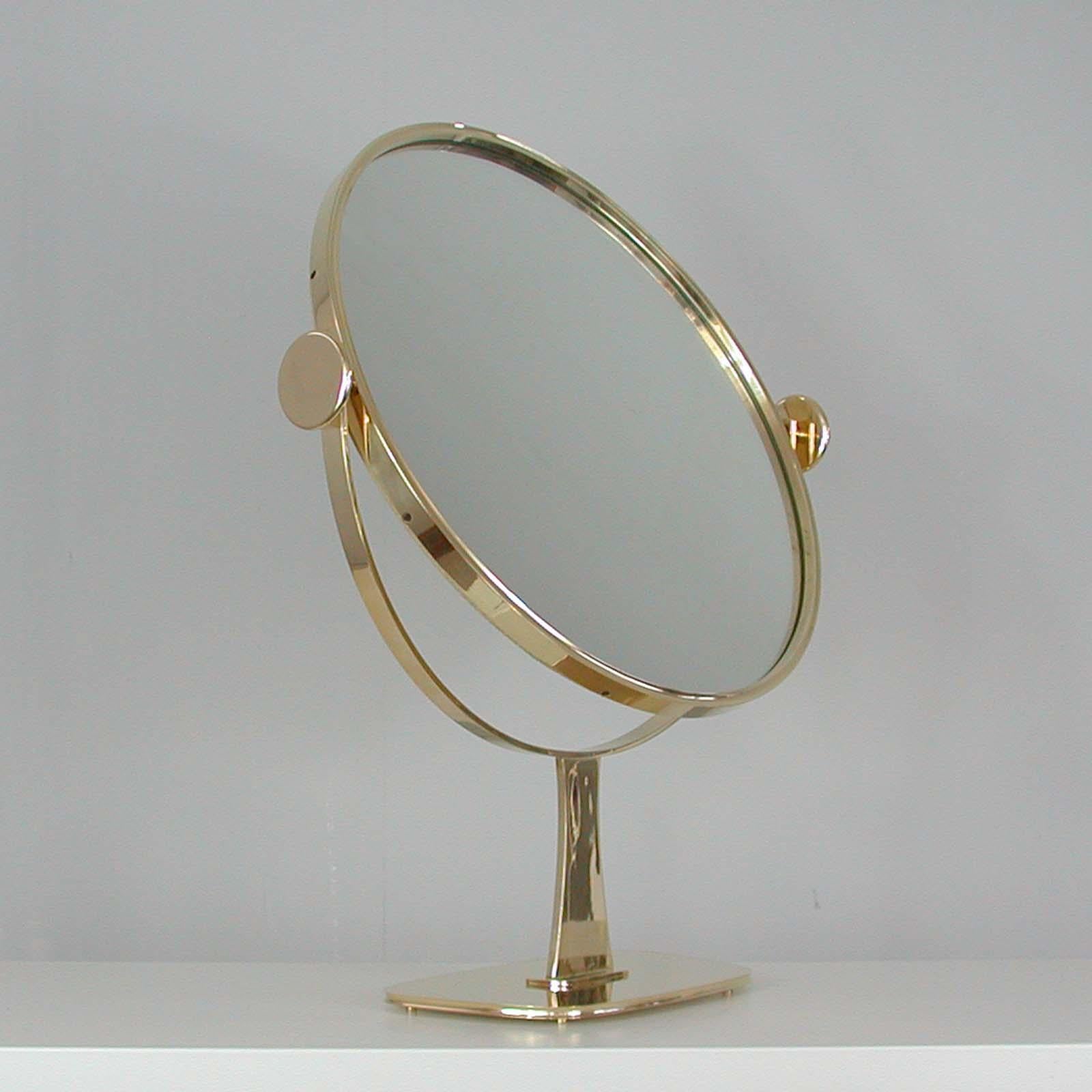 This awesome large vanity or table mirror was designed and manufactured in Germany in the 1960s by Vereinigte Werkstätten Munich. It features a brass frame on a trapezoidal brass foot. The rear is covered with cream colored wild silk.

The mirror