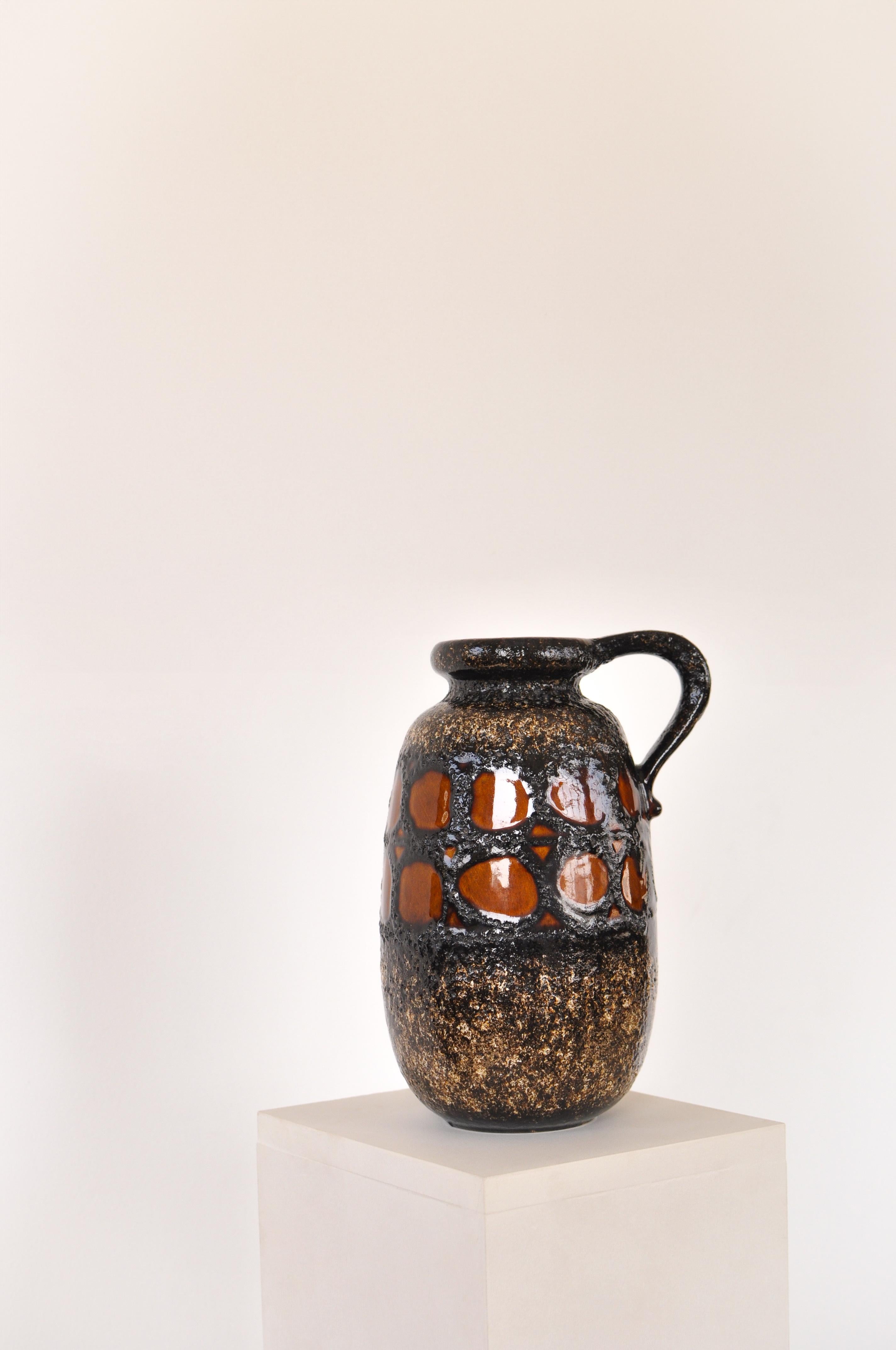 Glazed fat lava ceramic vase produced in East Germany number 484-27. Brown background textured details in black and orange. Piece with marking on the bottom.