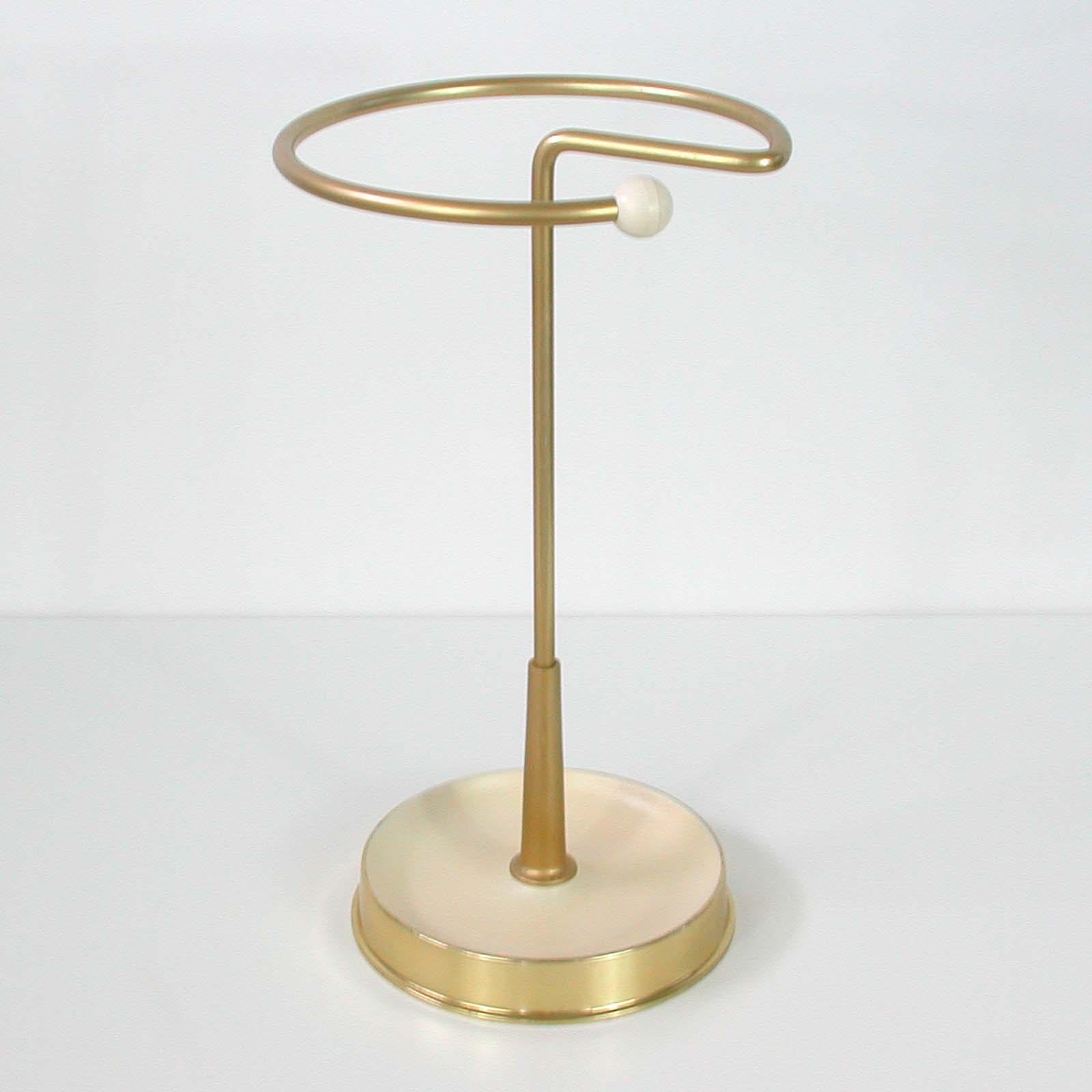 This Bauhaus inspired atomic umbrella stand was made in Germany in the 1950s.
It is made of gold anodized metal and has got a cream lacquered brass base.
  