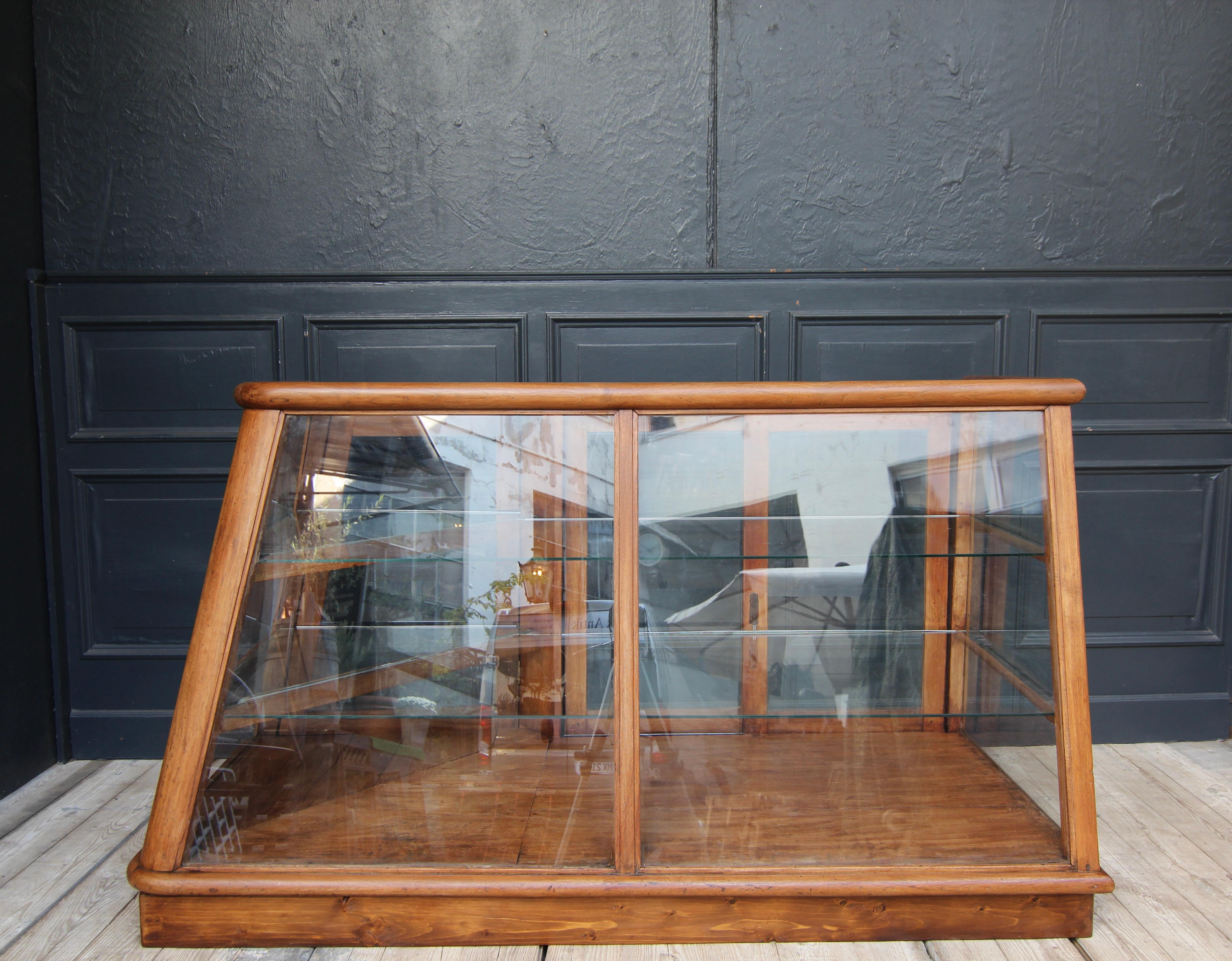 German Vintage shop counter. Circa from the 1920s/ 30s. 

On an asymmetrical ground plan, the oak wood corpus is tapered towards the top, rounded and glazed all around. Rear side with 2 sliding doors and a further lockable door hinged on the