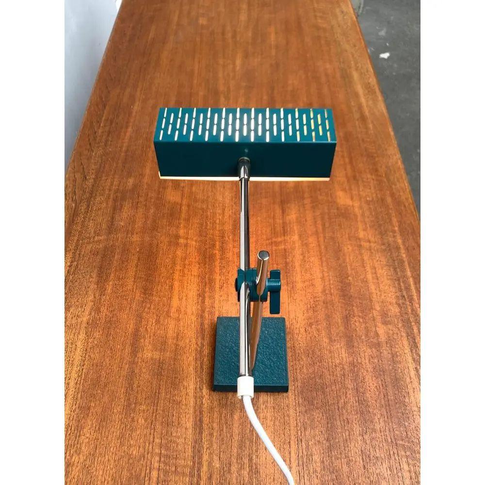 Minimalist Mid-Century table lamp from Leclaire & Schäfer.

A very straight design. The cuboid -shaped light head is made of green -painted metal sheet. As a diffuser, a translucent acrylic pane is inserted as a diffuser. There is a striking