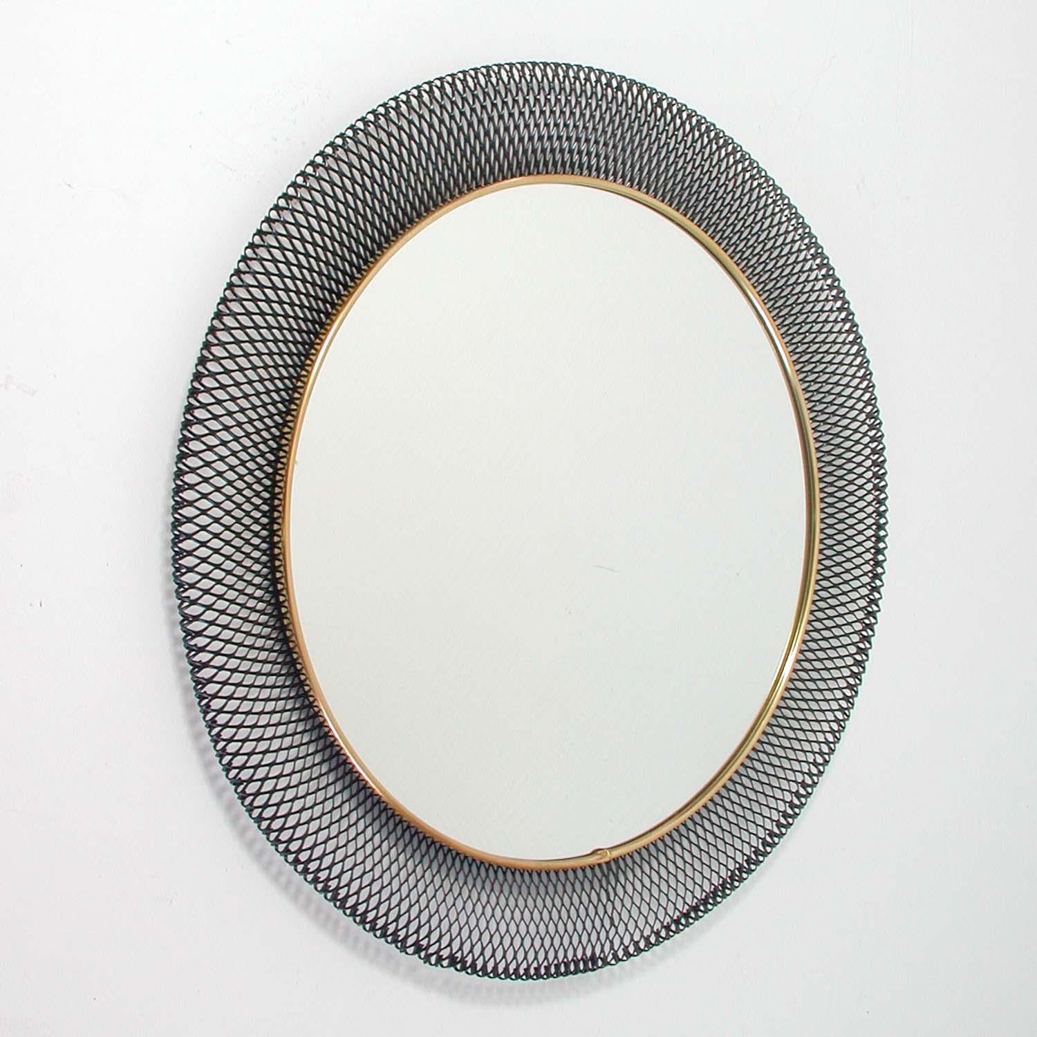 This beautiful round midcentury wall mirror was designed and manufactured in Germany in the 1950s by Vereinigte Werkstätten München. It is made of black lacquered stretched metal in the manner of French Designer Mathieu Mategot and has got a