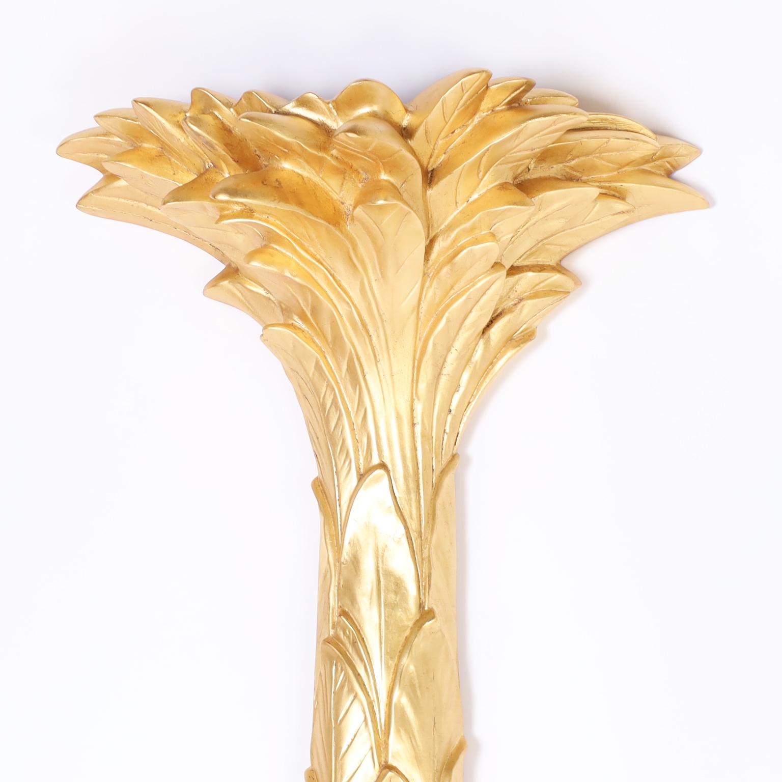 Mid-century Serge Roche style wall mounted palm tree torchiere crafted in cast composition and featuring an alluring lush gilded finish.