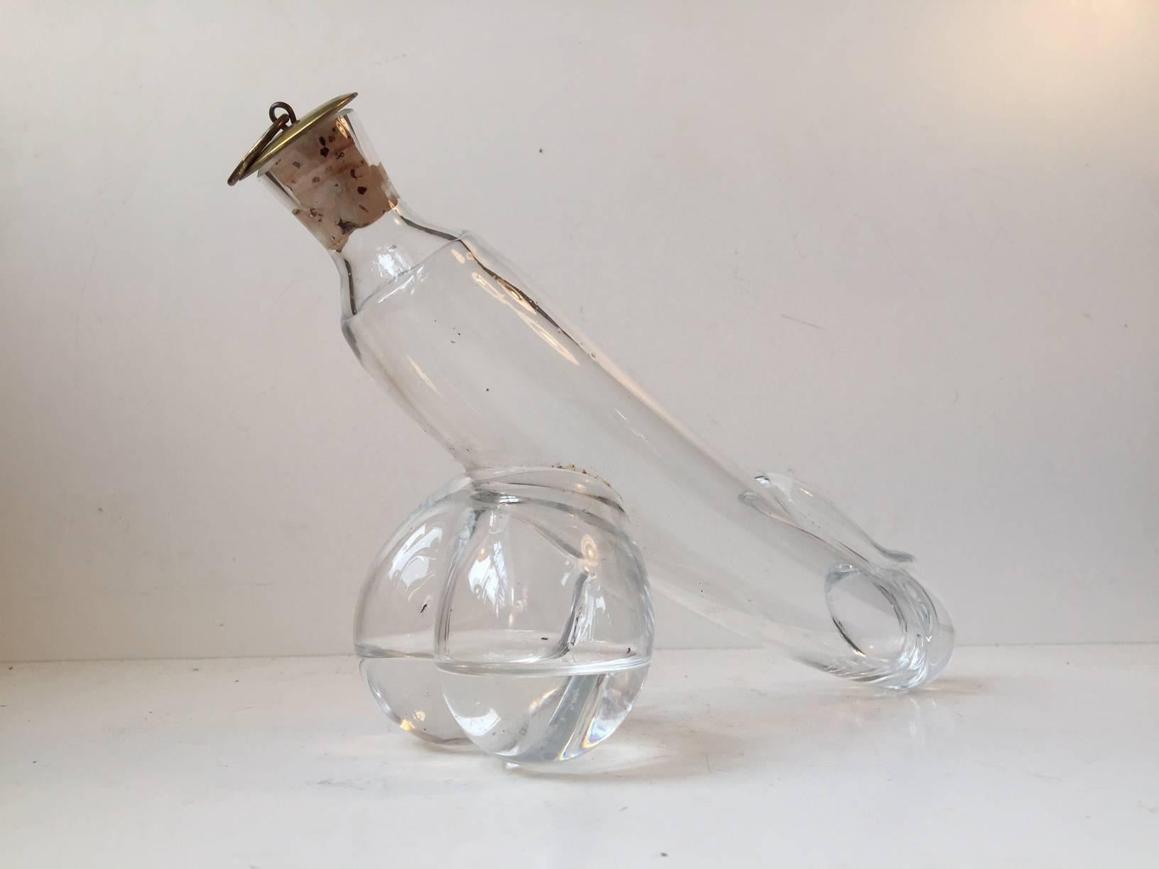 A mouth blown clear glass erotic decanter in shape of a Fallos/Penis. These curious decanters were made by employees at Holmegaard in Denmark during the 1960s and 1970s. It features its original brass/cork stopper and can contain approximately 0.5