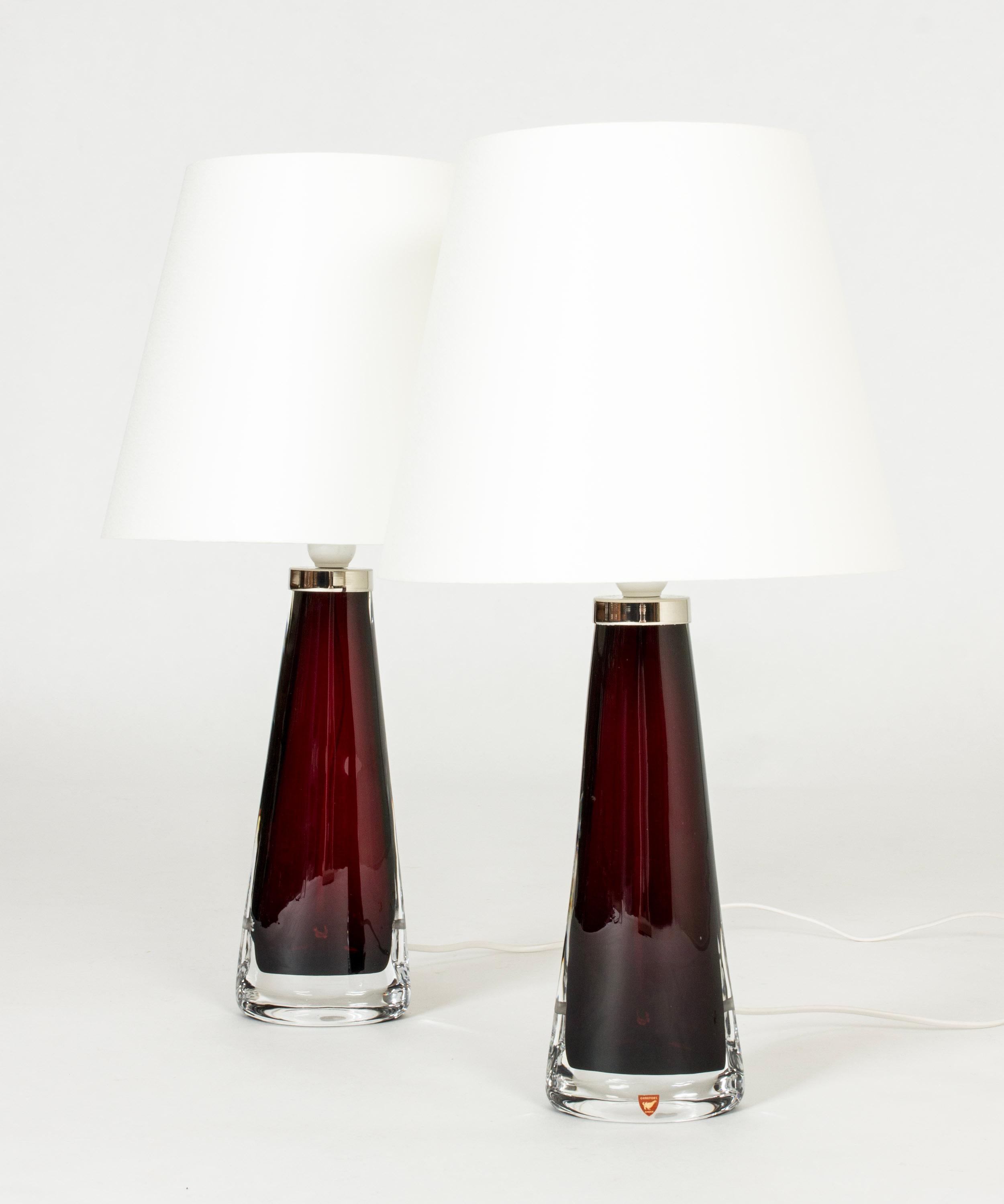 Pair of crystal glass table lamps by Carl Fagerlund, made from burgundy colored glass in a narrow conical shape, almond shaped at the base. Beautiful translucent color, elegant design.