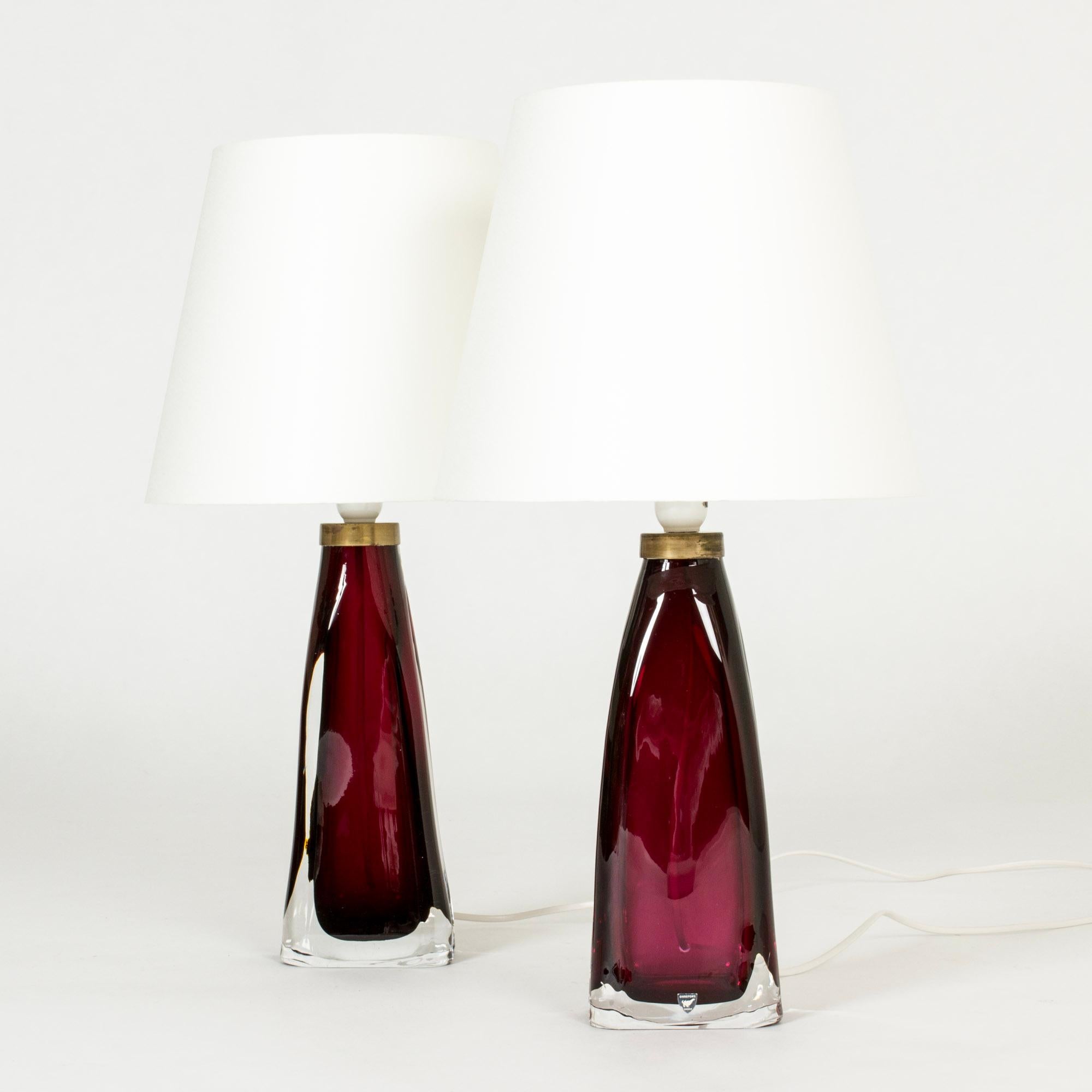 Pair of raspberry red glass table lamps by Carl Fagerlund for Orrefors. Heavy glass bases with a somewhat undulating shape and brass detail at the top. Very elegant with movement in the design.