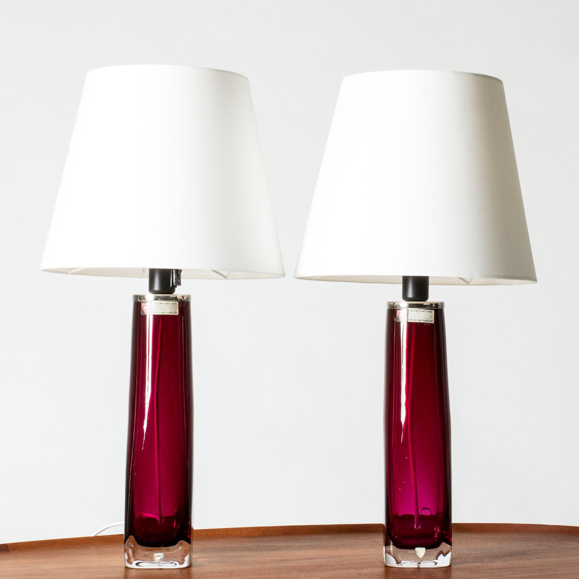 Paire de magnifiques lampes de table en verre translucide rouge framboise de Carl Fagerlund pour Orrefors. Bases en verre lourd avec une forme épurée et un détail en métal blanc au sommet. Joli dans une fenêtre.