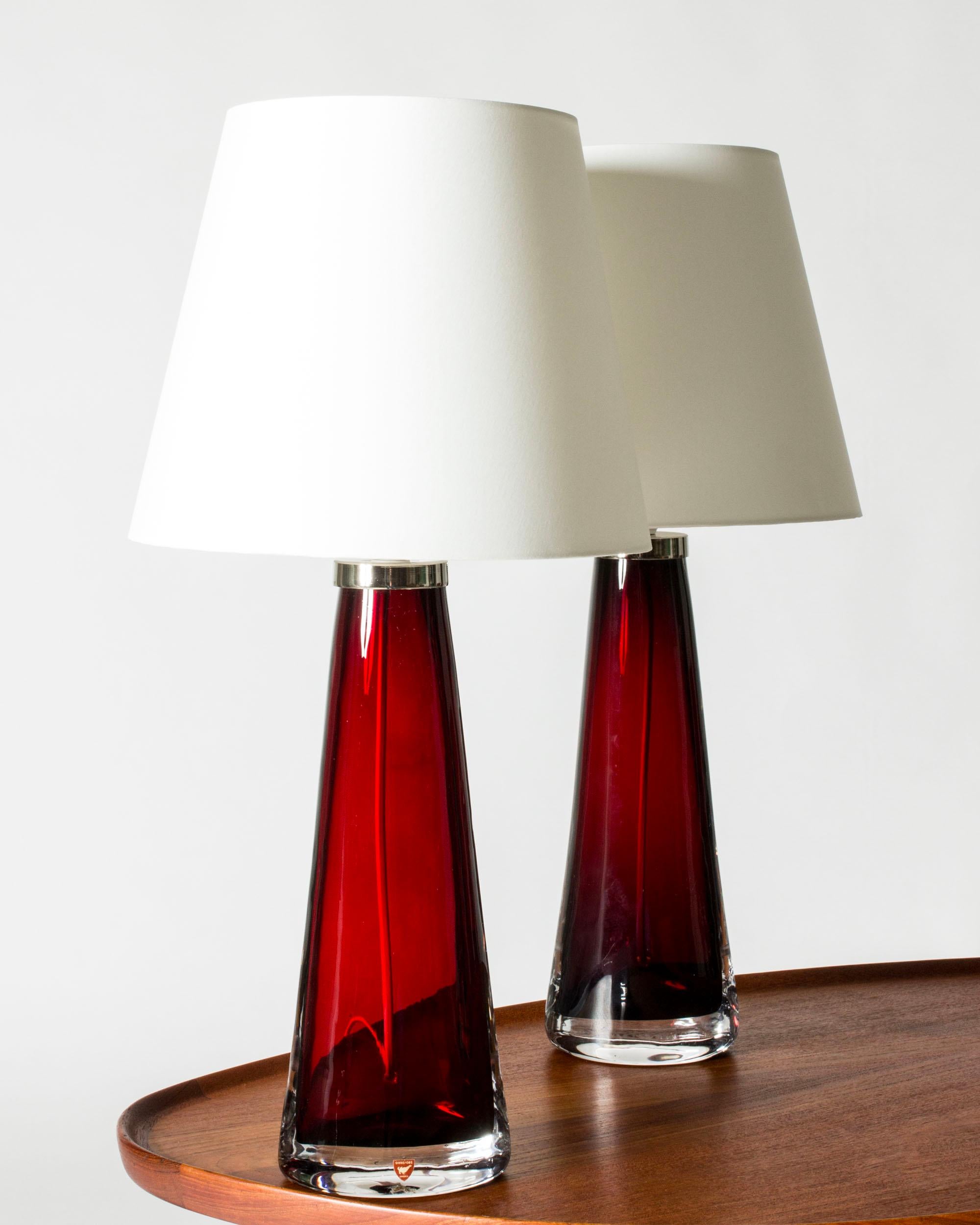 Pair of crystal glass table lamps by Carl Fagerlund, made from rich red colored glass in a tapering conical shape, almond shaped at the base. Beautiful translucent color, elegant design.