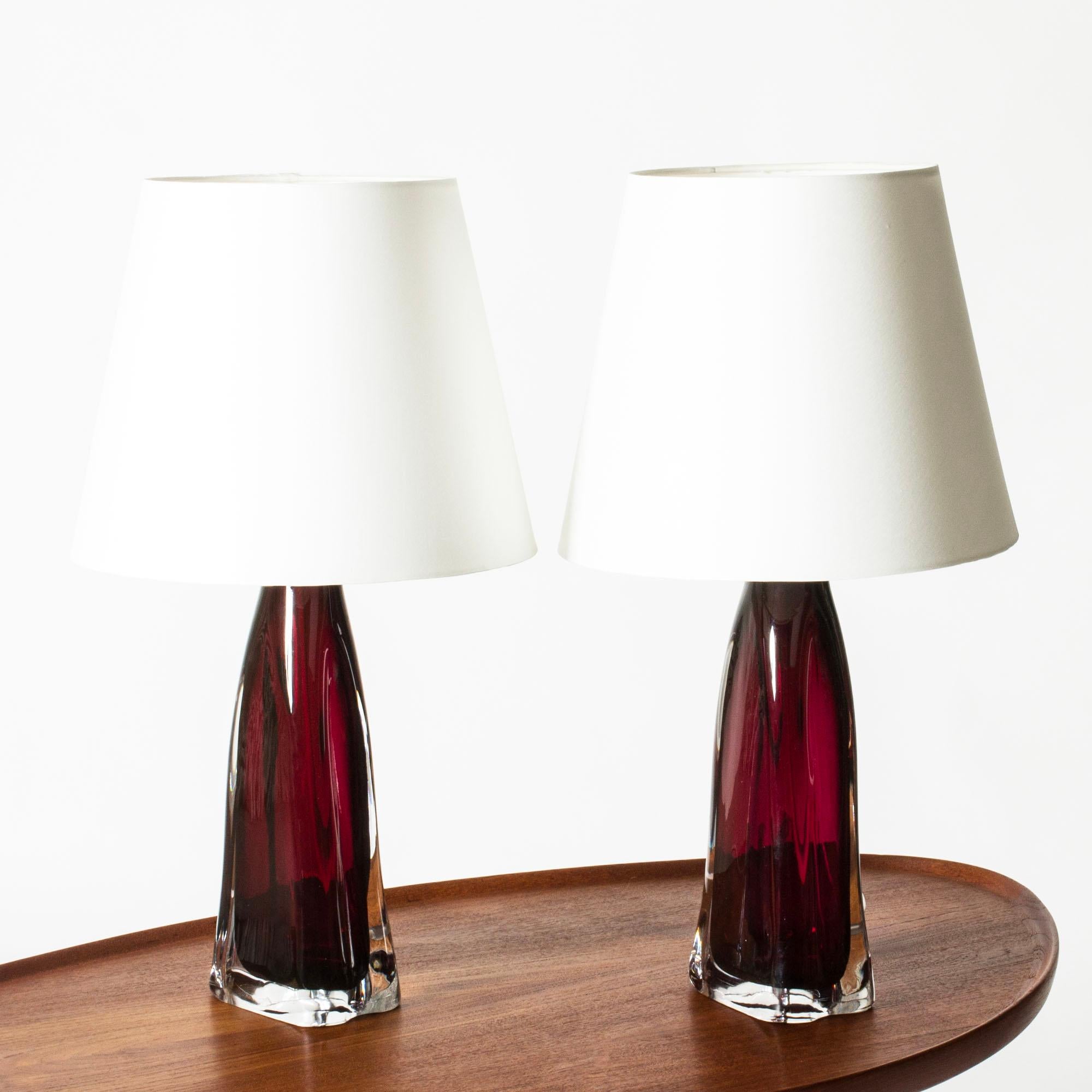 Pareja de lámparas de sobremesa de cristal rojo burdeos de Carl Fagerlund para Orrefors. Pesadas bases de cristal con forma algo ondulada y detalle de latón en la parte superior. Muy elegante con movimiento en el diseño.