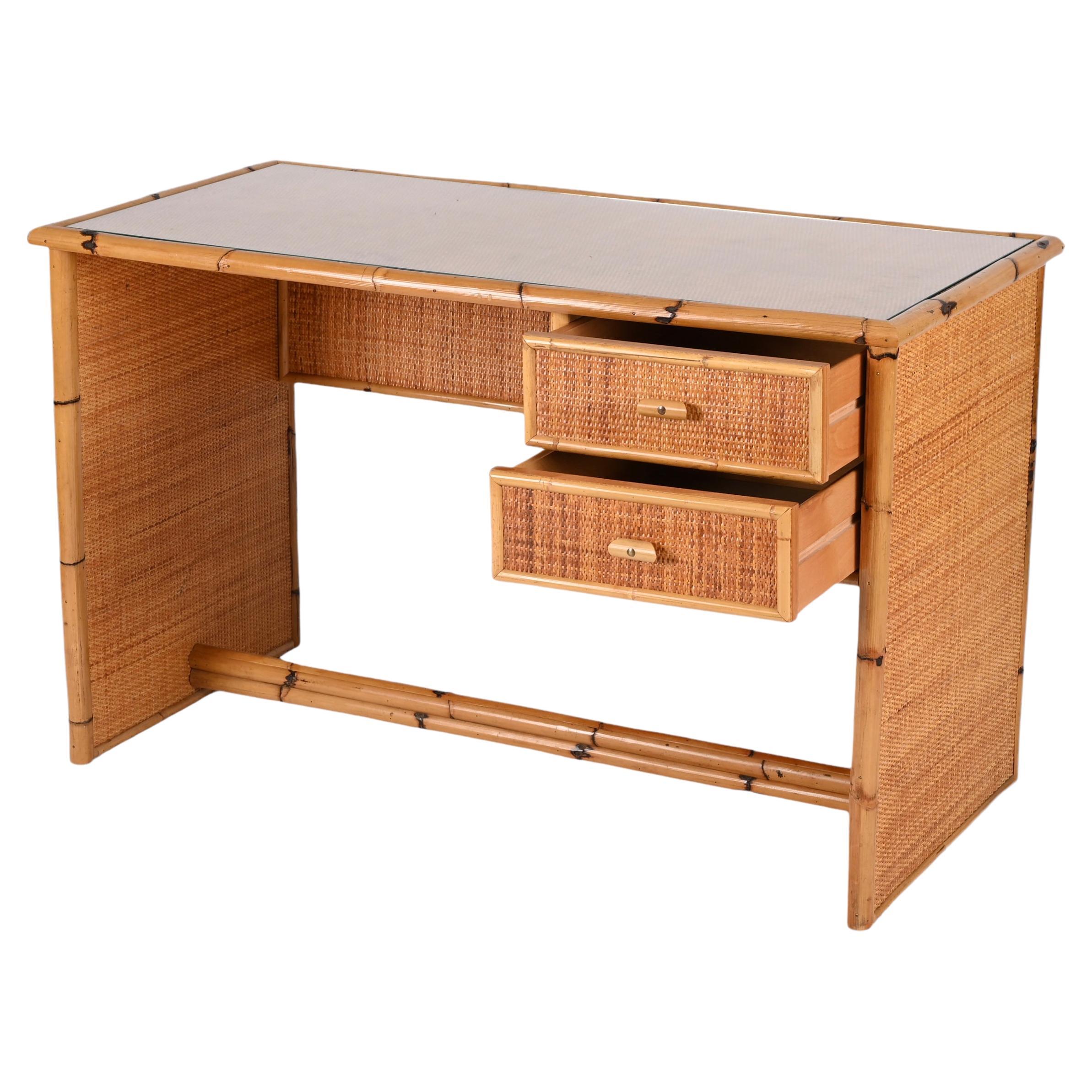 Midcentury glass top, bamboo and wicker desk with drawers. This excellent piece was designed in Italy in the 1980s.

This desk is unique for the materials used, bamboo and rattan, and has two drawers. The top is made of crystal glass and the
