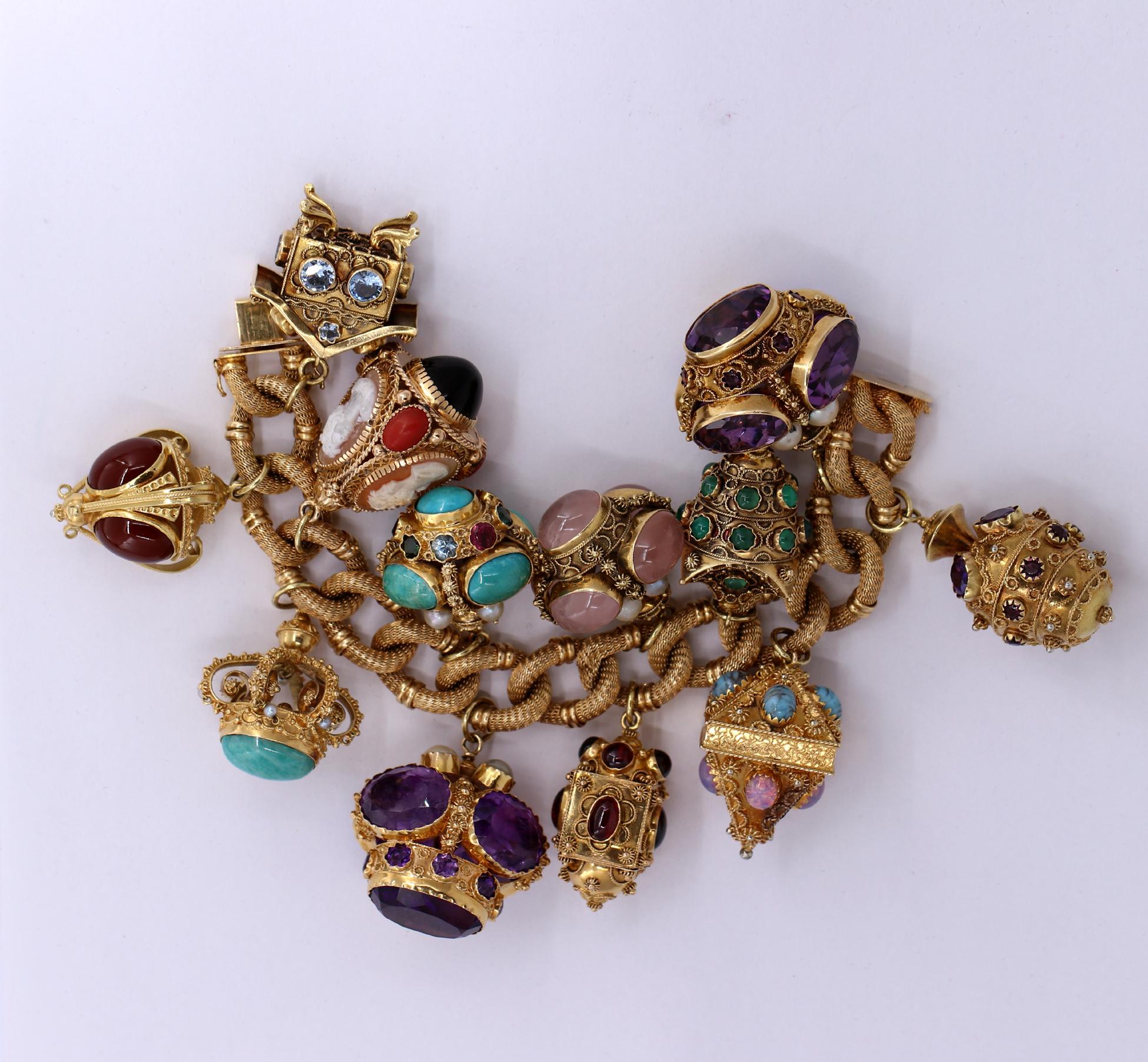 A ladies 18K yellow gold bracelet, with twelves charms, measuring 7 1/4 inches long. Each charm is set with semi-precious gemstones offering a variety of beautiful color. Sometimes referred to as 