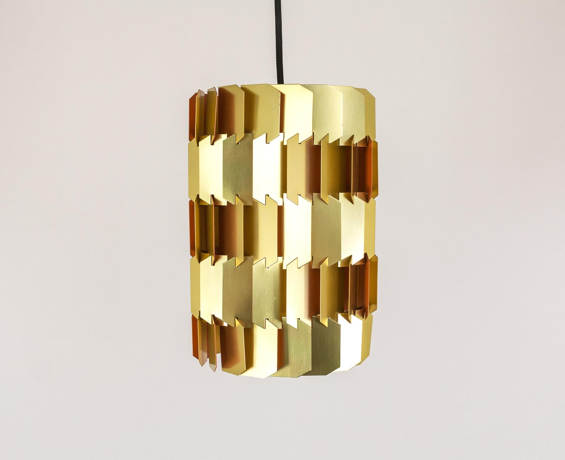 Louis Weisdorf, the distinguished Danish architect and designer, created this gold facet pendant light in 1963. 

The facet consists of 18 identically shaped shades. The construction of the lamp is a 3-D puzzle, as each piece fits into the