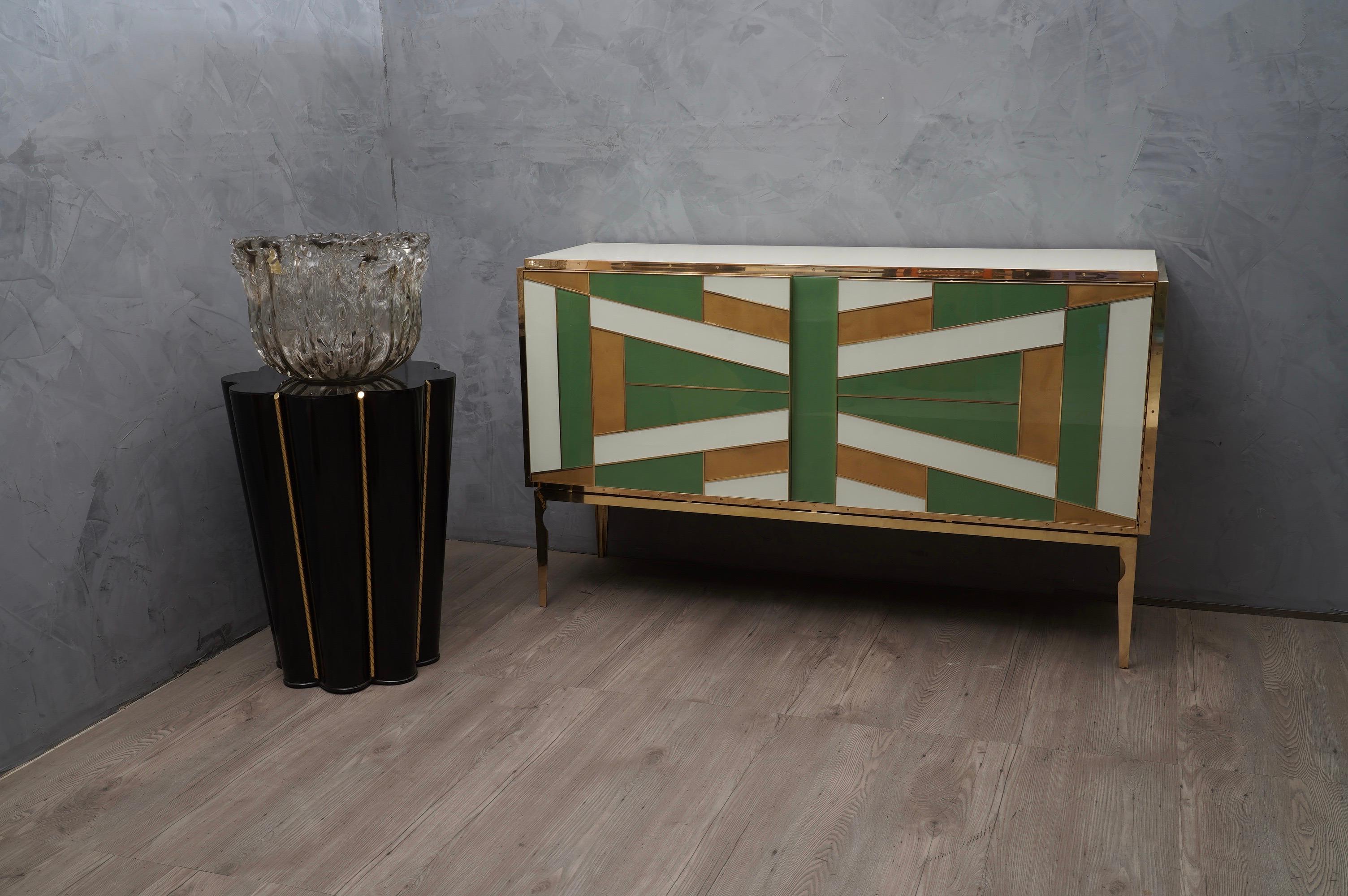 Very special multi-color glass sideboard beautifully matched with green gold and light ivory.

The sideboards have a wooden structure, externally they have been plated with glass of different colors and then edged with polished brass finishes. Brass
