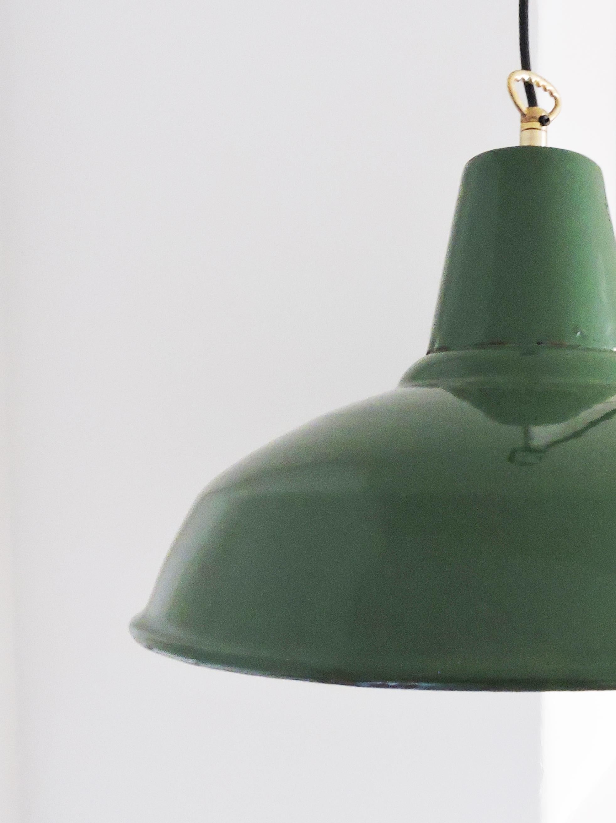A 1950s midcentury green industrial pendant light, 1950s. The light features a brass hook and hangs from black wire.

A professional electrician has rewired this piece to be in working order.
Plug Type - UK Plug (up to 250V).