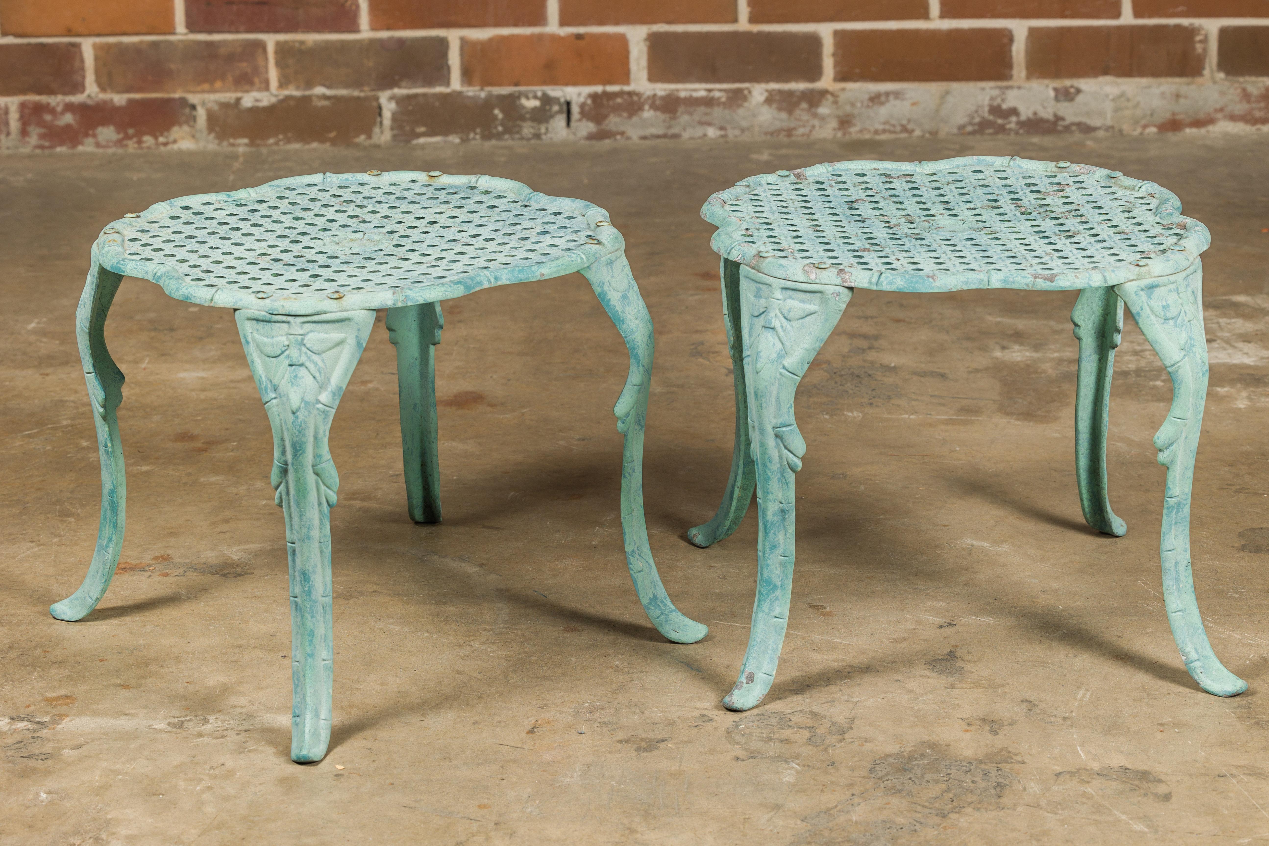 A pair of French painted cast iron low side tables from the Midcentury period, with blue green finish, wicker inspired top and cabriole legs. Discover the elegance and charm of these Midcentury French cast iron side tables, a delightful pair that