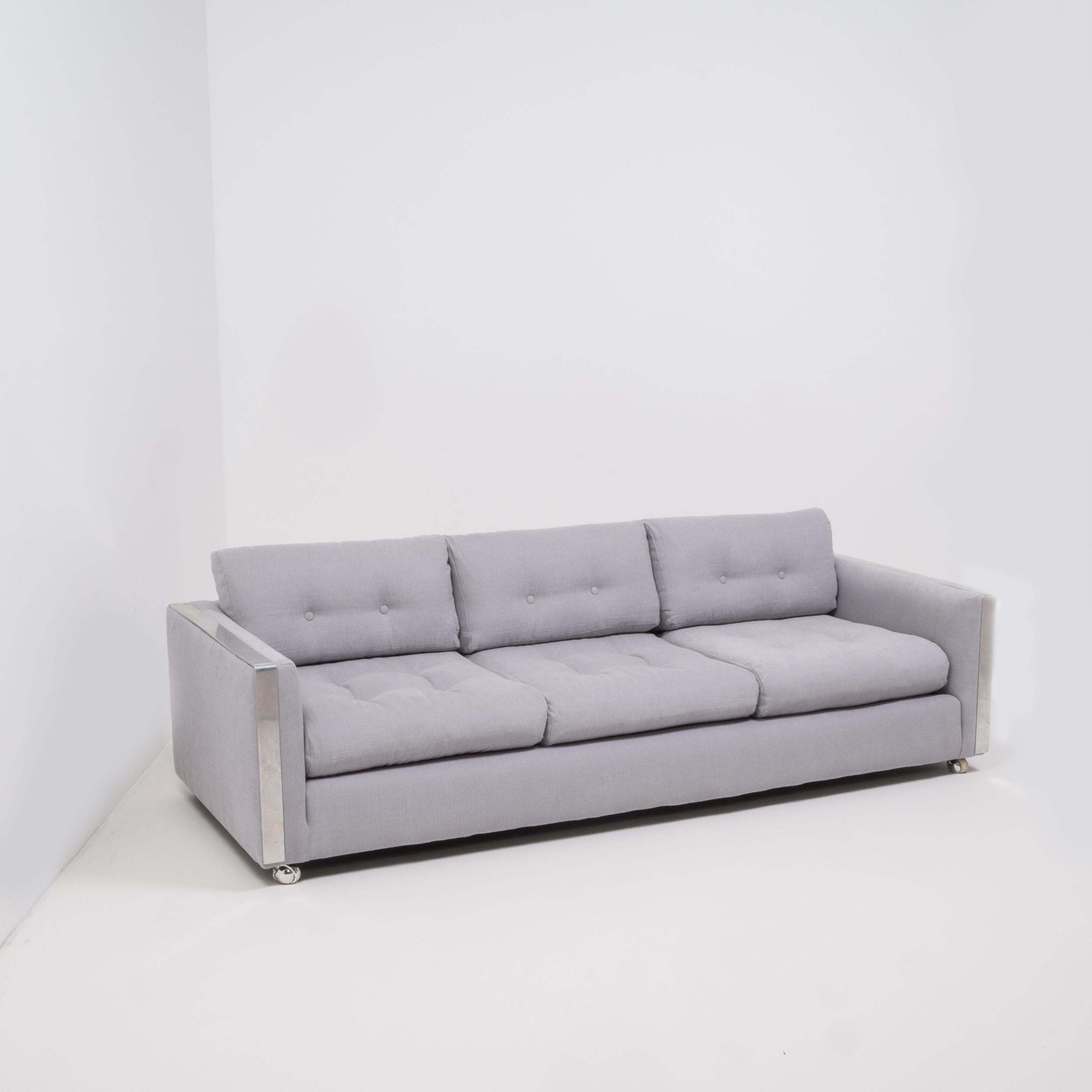 Designed in the style of Milo Baughman, this sleek three-seat sofa has been newly upholstered in a sumptuously soft and airy grey Linara fabric that compliments the chrome detailing perfectly.
 
With its clean lines and cool aesthetic it combines