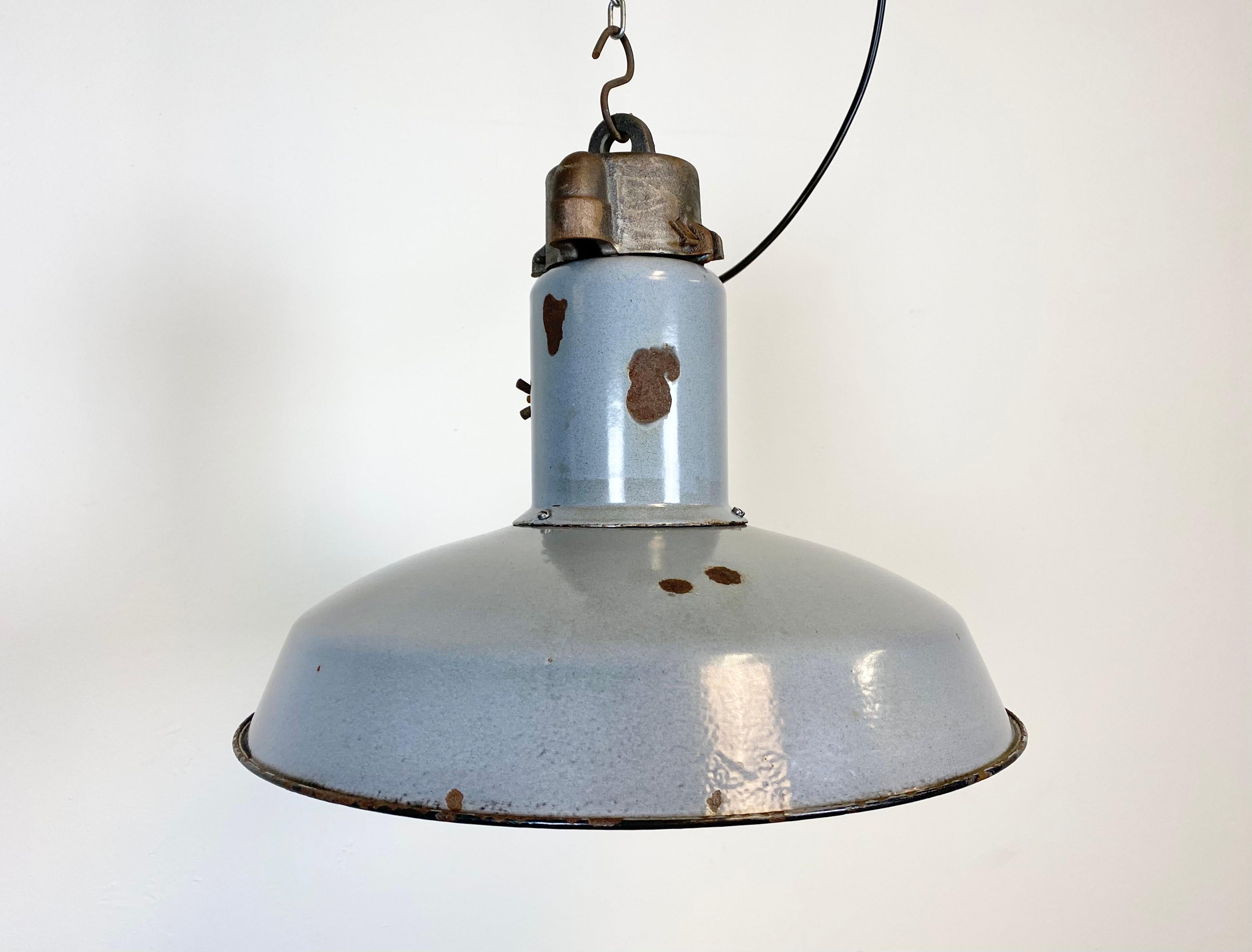 This Industrial grey enamel pendant lamp was manufactured during the 1950s in former Czechoslovakia. The lamp has white enamel interior and cast iron top. New porcelain socket for E 27 lightbulbs and new wire. The weight of the lamp is 3 kg.
