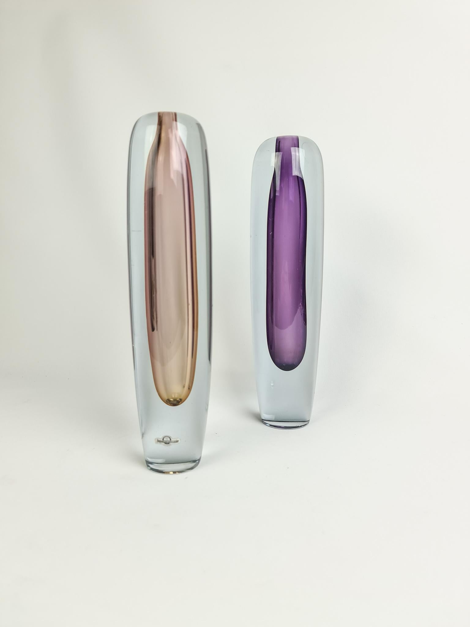 Wonderful tall glass vases designed by famous Gunnar Nylund and produced between 1952-1955 Strömbergshyttan in Sweden.
This set of 2 tall vases are wonderful sculptured and with its colored inside it gives a beautiful light when struck by a light.