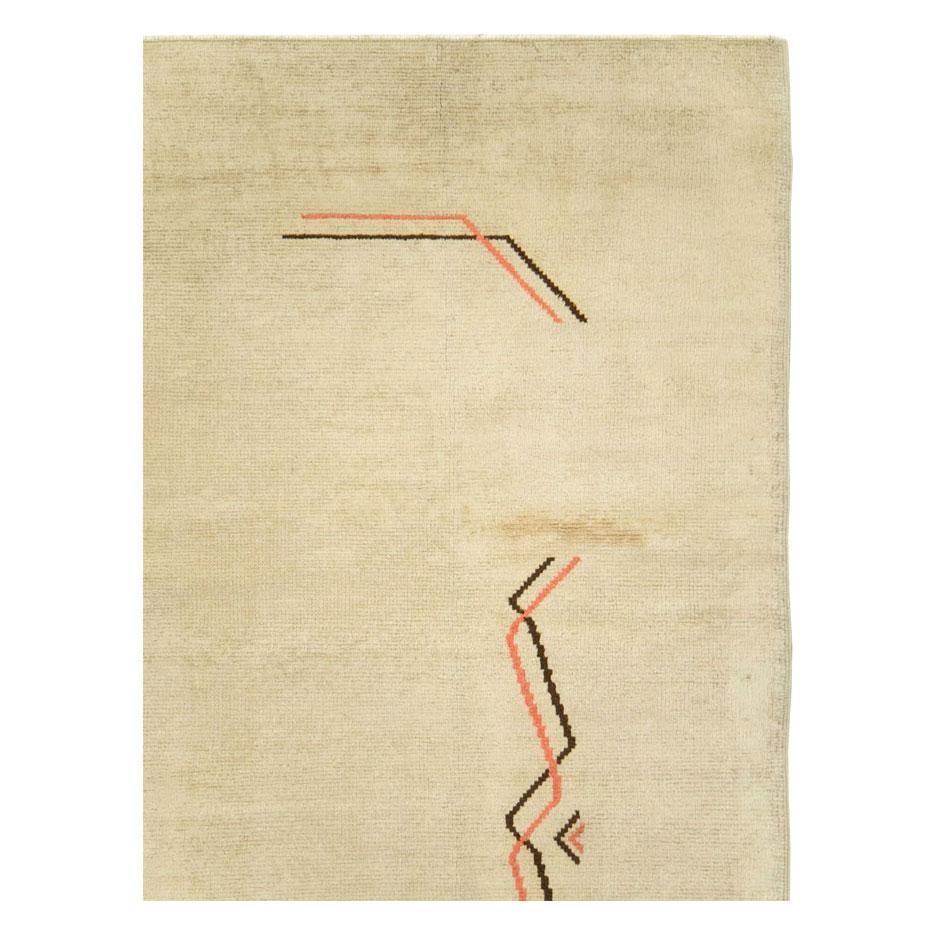 A vintage European Art Deco rug handmade during the mid-20th century with an open field cream background in the borderless moderne style. Abstract orange and brown zigzag lines are the only motifs that decorate the otherwise minimalist