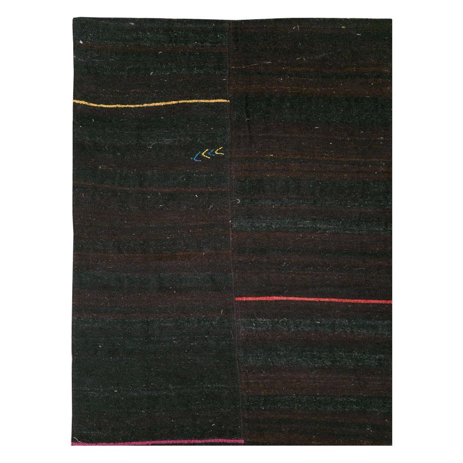 A modern Persian flat-weave Kilim accent rug from the 21st century with four dark brown sections stitched together due to its nomadic nature. The blue, white, red, pink, and yellow stripes add a bit of vibrancy to the otherwise mellow