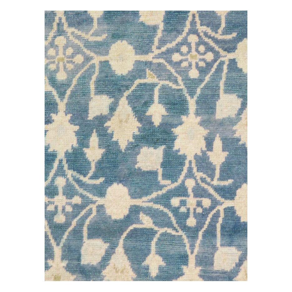 A vintage Turkish Anatolian throw rug handmade during the mid-20th century. The borderless cerulean blue field consists of large scale ivory colored vines and flowers with hints of green within. Folk by tradition, yet modern by design.