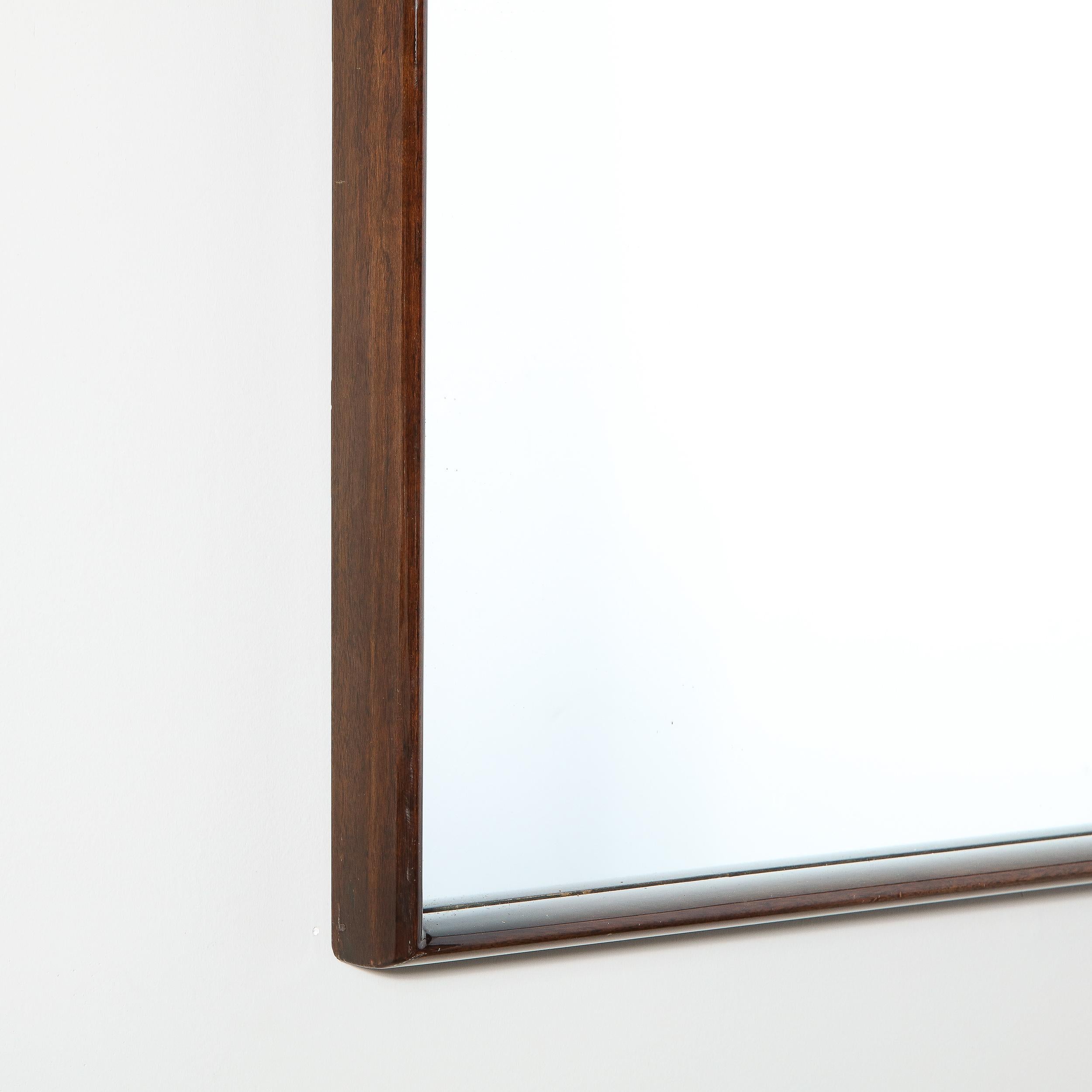 This elegant and austere mirror was designed by the legendary T.H. Robsjohn-Gibbings for Widdicomb Co. in the United States, circa 1950. It offers a clean rectangular shadowbox frame in handrubbed walnut circumscribing a plain mirror center. This