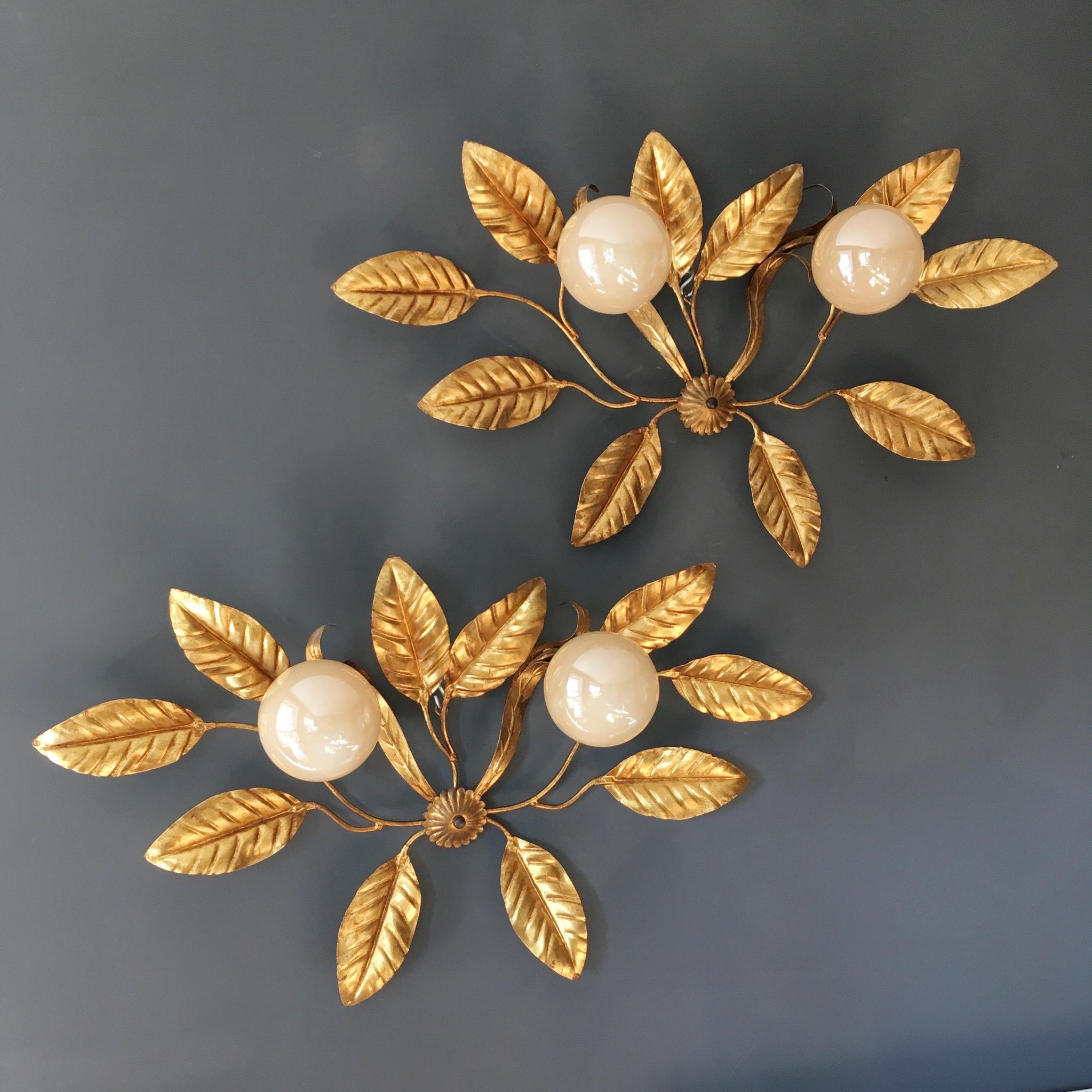 Stunning 1960s-1970s wall sconces.

In the style of Hans Kogl

Large gilt leaves branch from multiple stems, 2 of these stems support 2 soft peach coloured iridescent glass globe shades

The lights have a small rose bottom centre where the