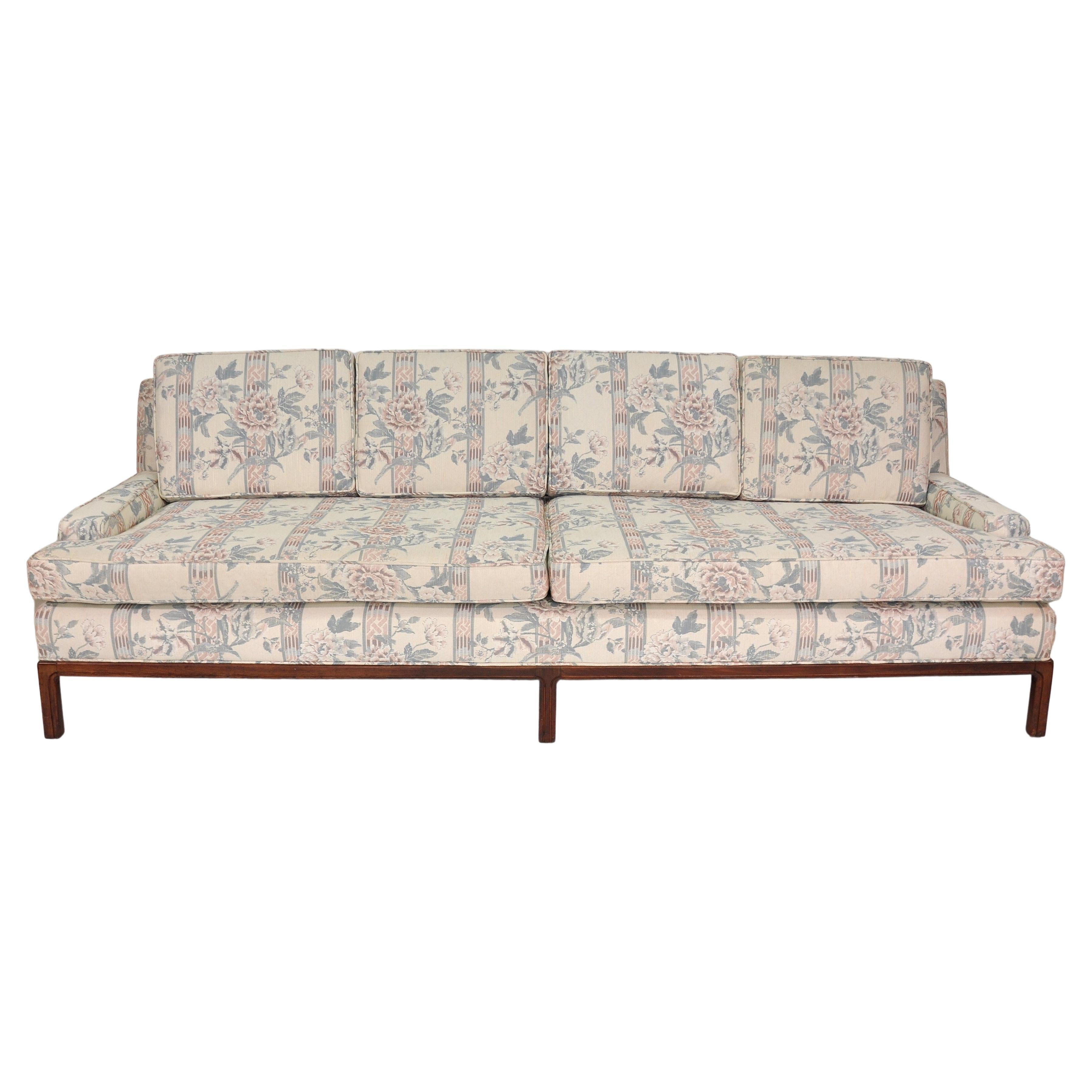 Grande divano vintage a quattro posti in tessuto bianco sporco con accenti color malva e azzurro, con righe geometriche e motivi floreali con rose. Il divano di metà secolo presenta uno stile con braccioli a basso profilo e una posizione di seduta