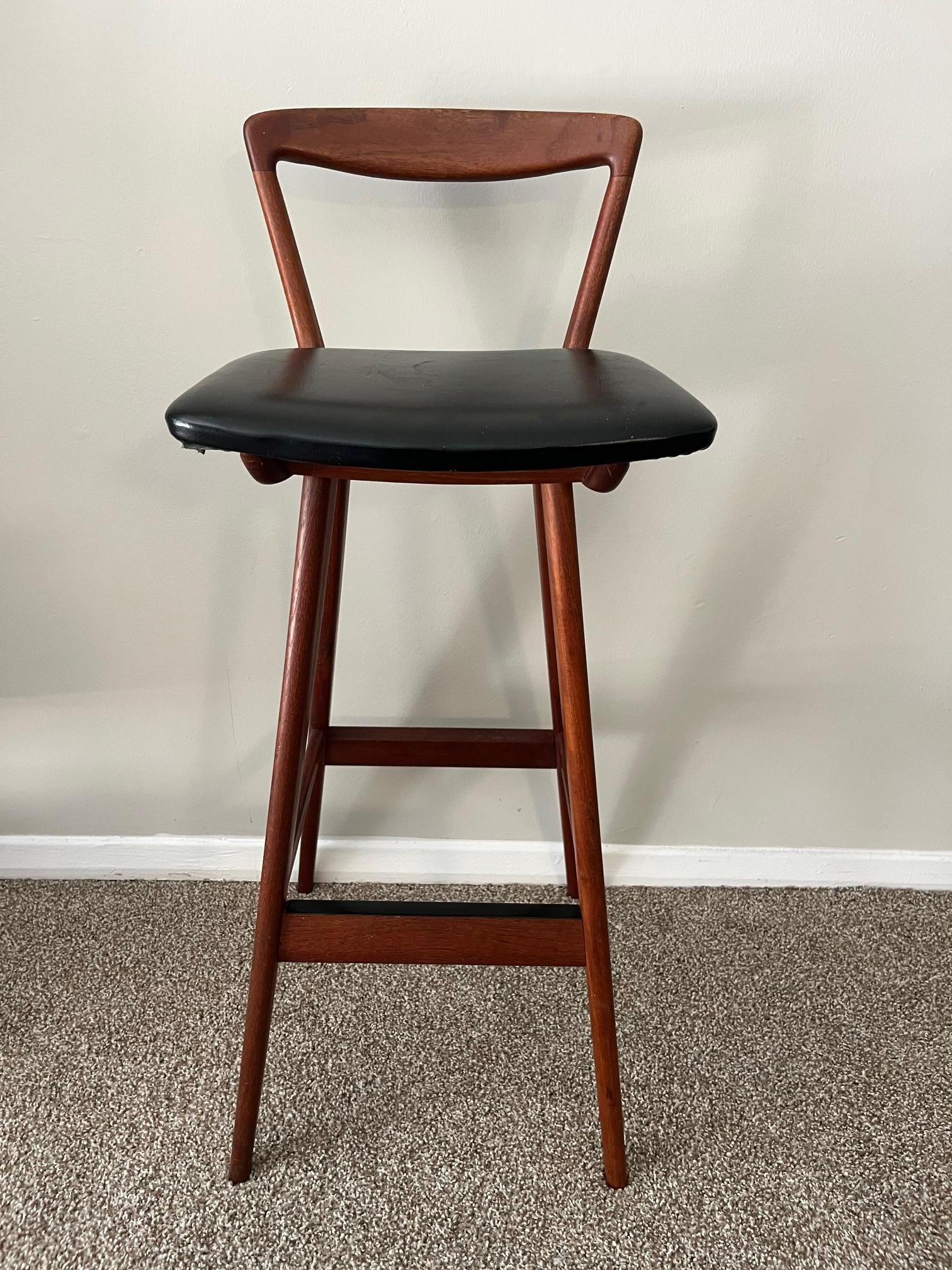 Tabouret de bar en teck du milieu du siècle dernier, conçu par Henry Rosengren Hansen pour Brande Mobelfabrik modèle 43, Danemark. Tabouret de bar en teck massif, dossier élégamment sculpté avec l'assise originale en vinyle noir, reposant sur des