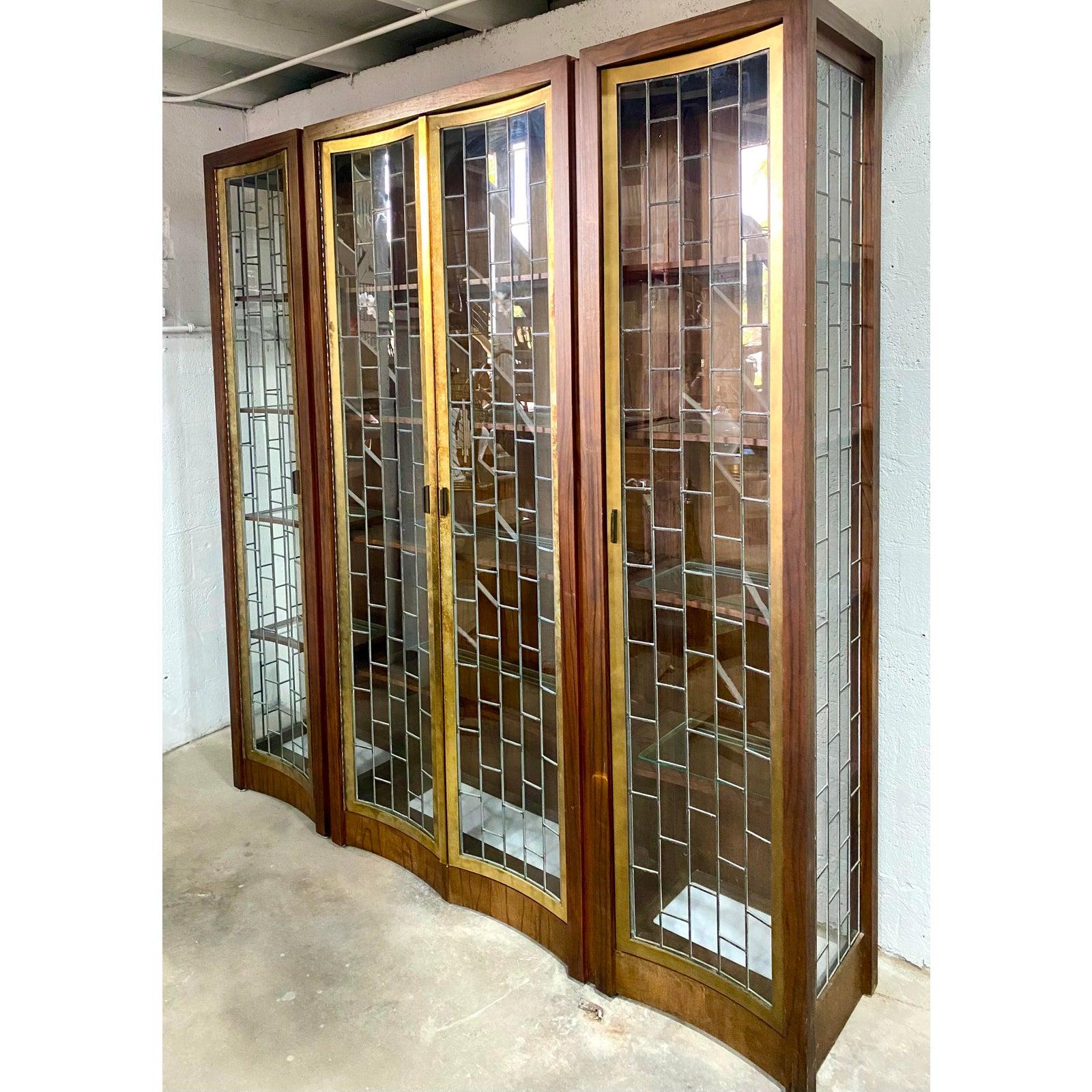 Stunning Vintage Heritage etagere. Beautiful curved leaded glass door. Lighting in the top and the bottom with inset glass shelves. Brass trim around each panel. Breaks down into three sections for easy movement.