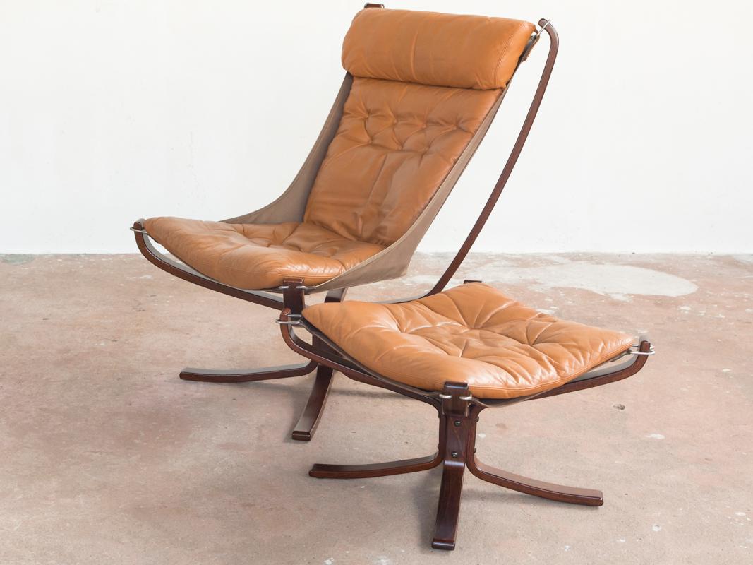 Midcentury Falcon chair and ottoman designed by Sigurd Ressell and manufactured by Vatne Møbler in Norway in the 1970s. It is the model with high back and padded leather. The frame is in dark stained beech, the canvas is dark brown, and the cushion