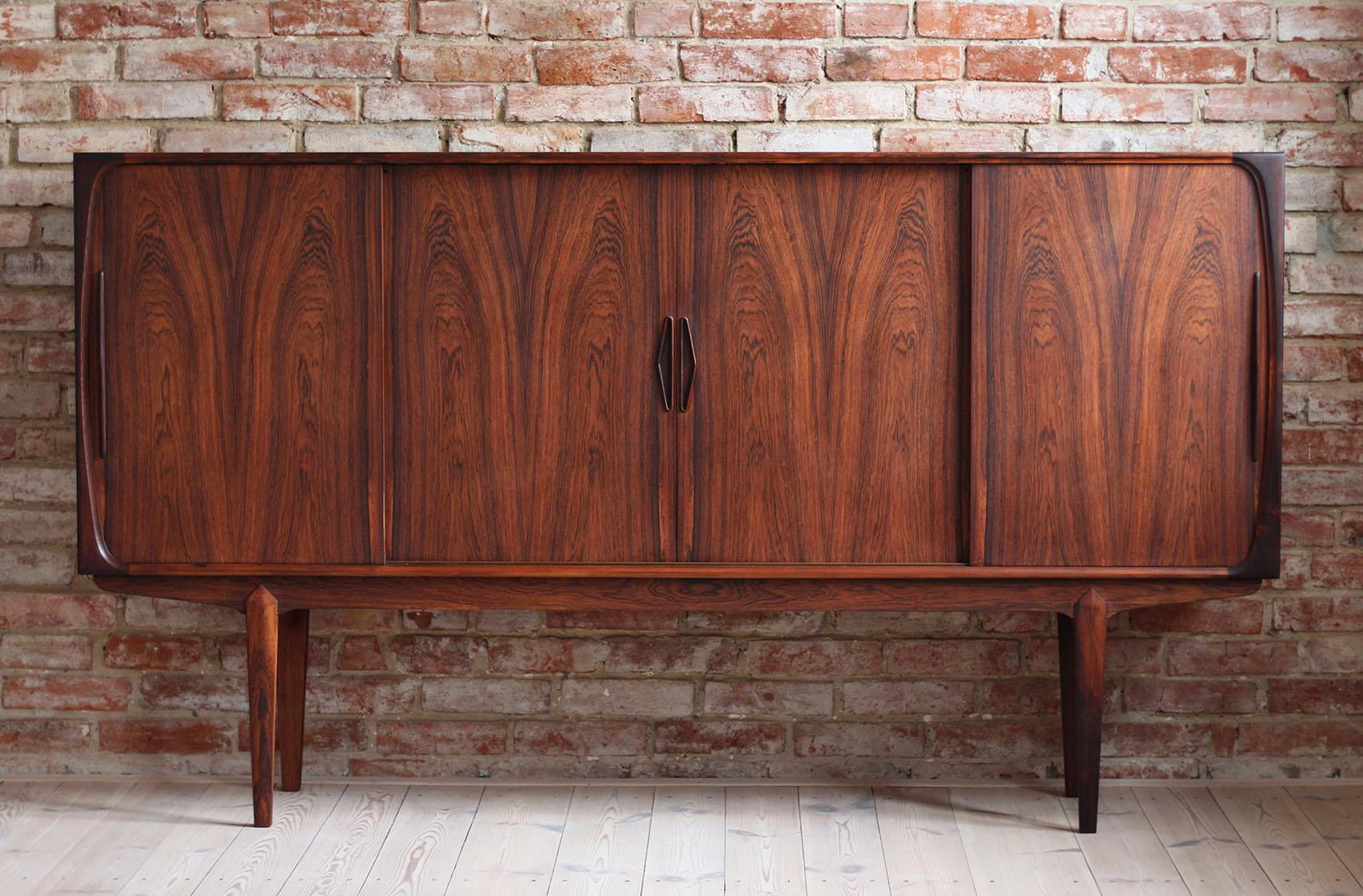 Danish Highboard in beautiful wood veneer. The piece was designed and made in 1960s and is a great example of Danish midcentury design in its best. It features four storage sections that provide lots of space and are easily accessible with sliding