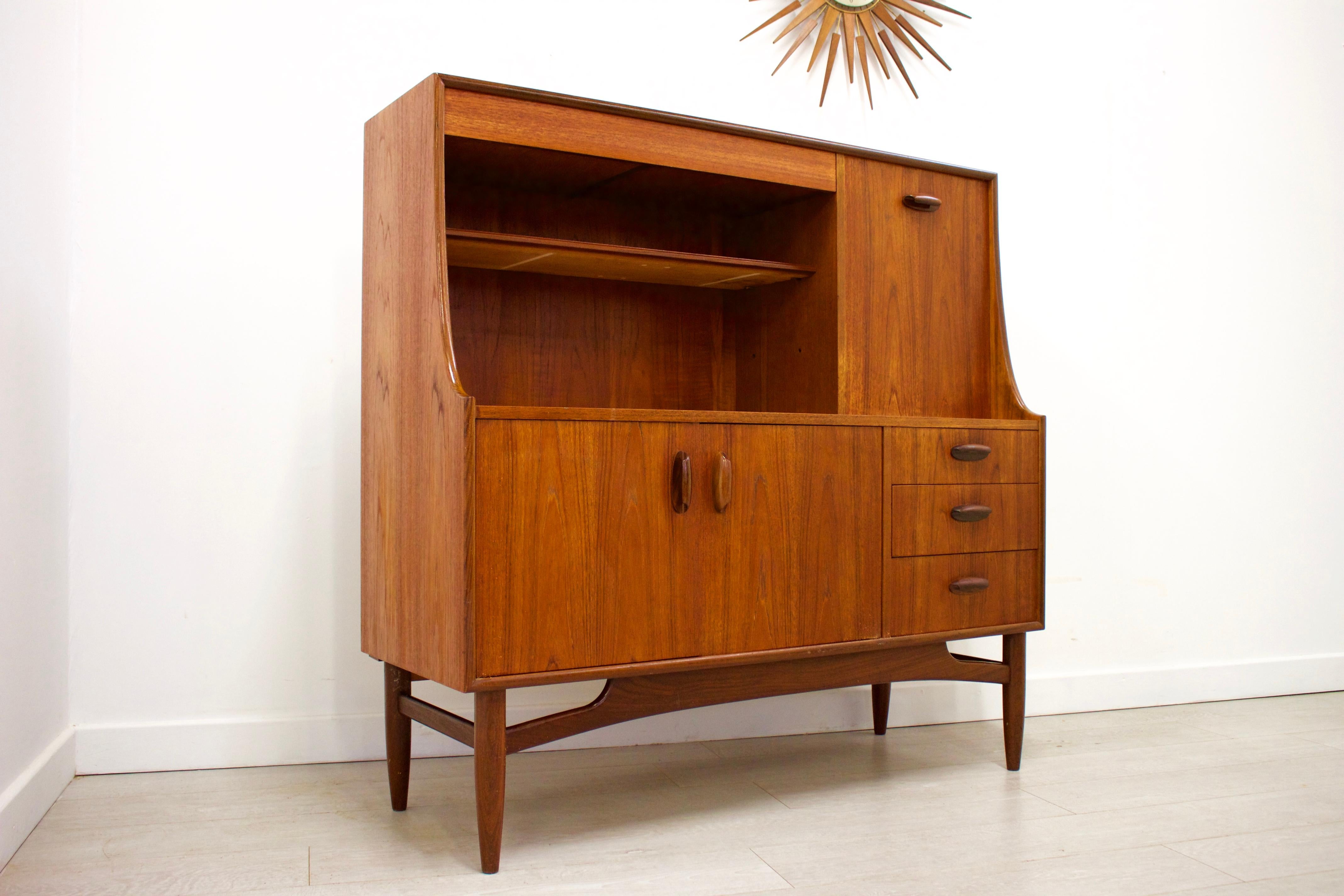 - Mid-Century Modern compact highboard or sideboard
- Featuring a pull down drinks cabinet
- Manufactured by G Plan in the UK
- Made from teak and teak veneer.
 