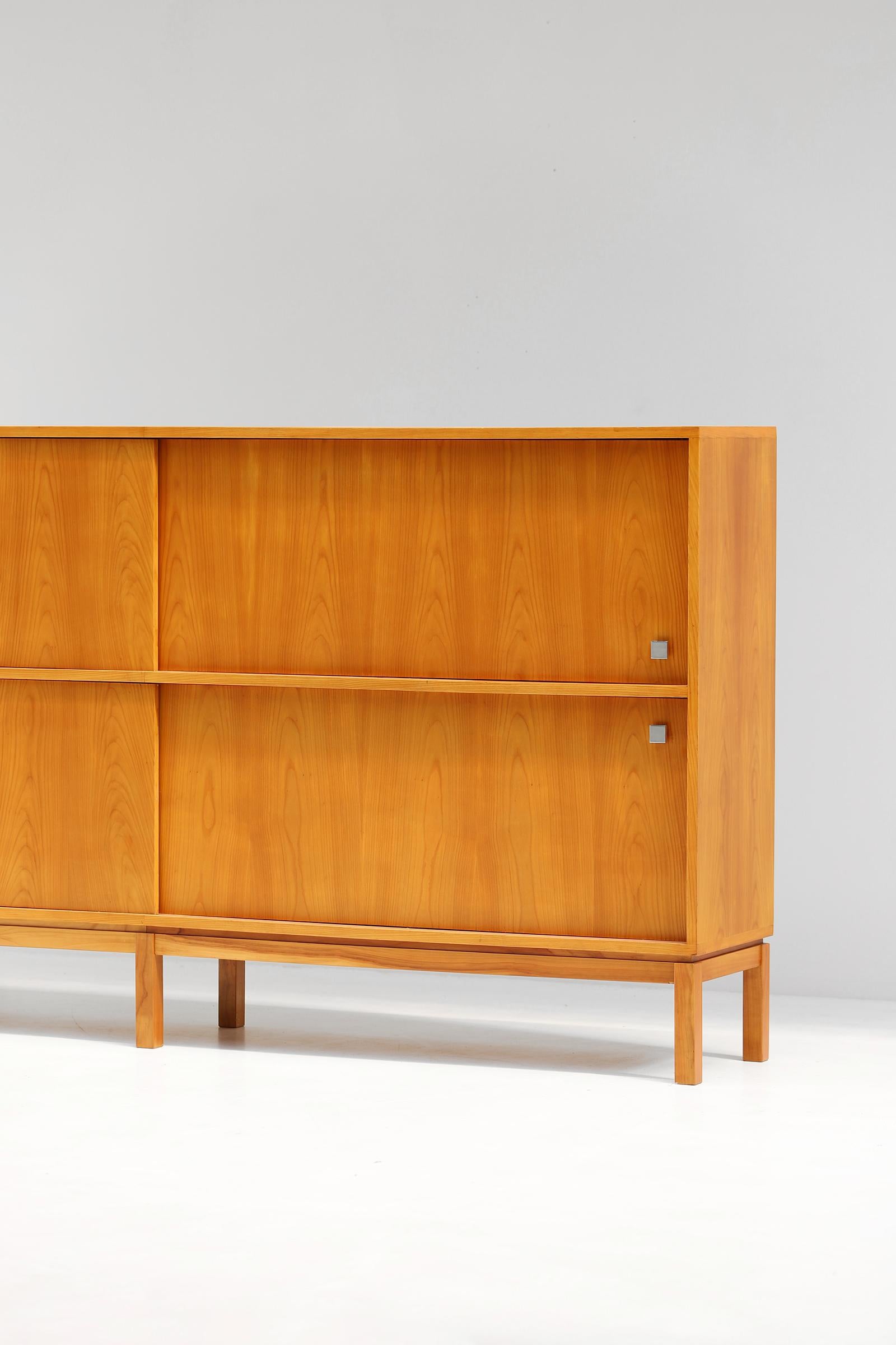 Large honeycolored highboard designed by Alfred Hendrickx for Belform in the 1960s. This spacious sideboard has 4 sliding doors with shelves and drawers behind. The doors are detailed with a square steel handle. The honey color brightens the design,
