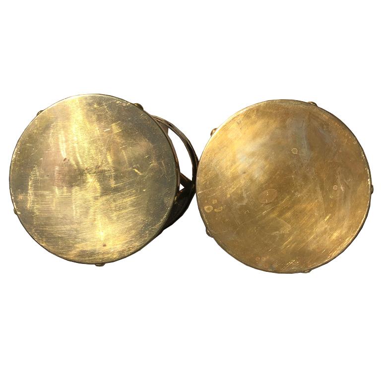 Mid-Century Modern pair of polished brass stools or side tables with X detailing around a solid copper/brass top. Circular rivets are placed around each band which wraps across the piece. Bottoms have a single strip of brass, with a small lip. The