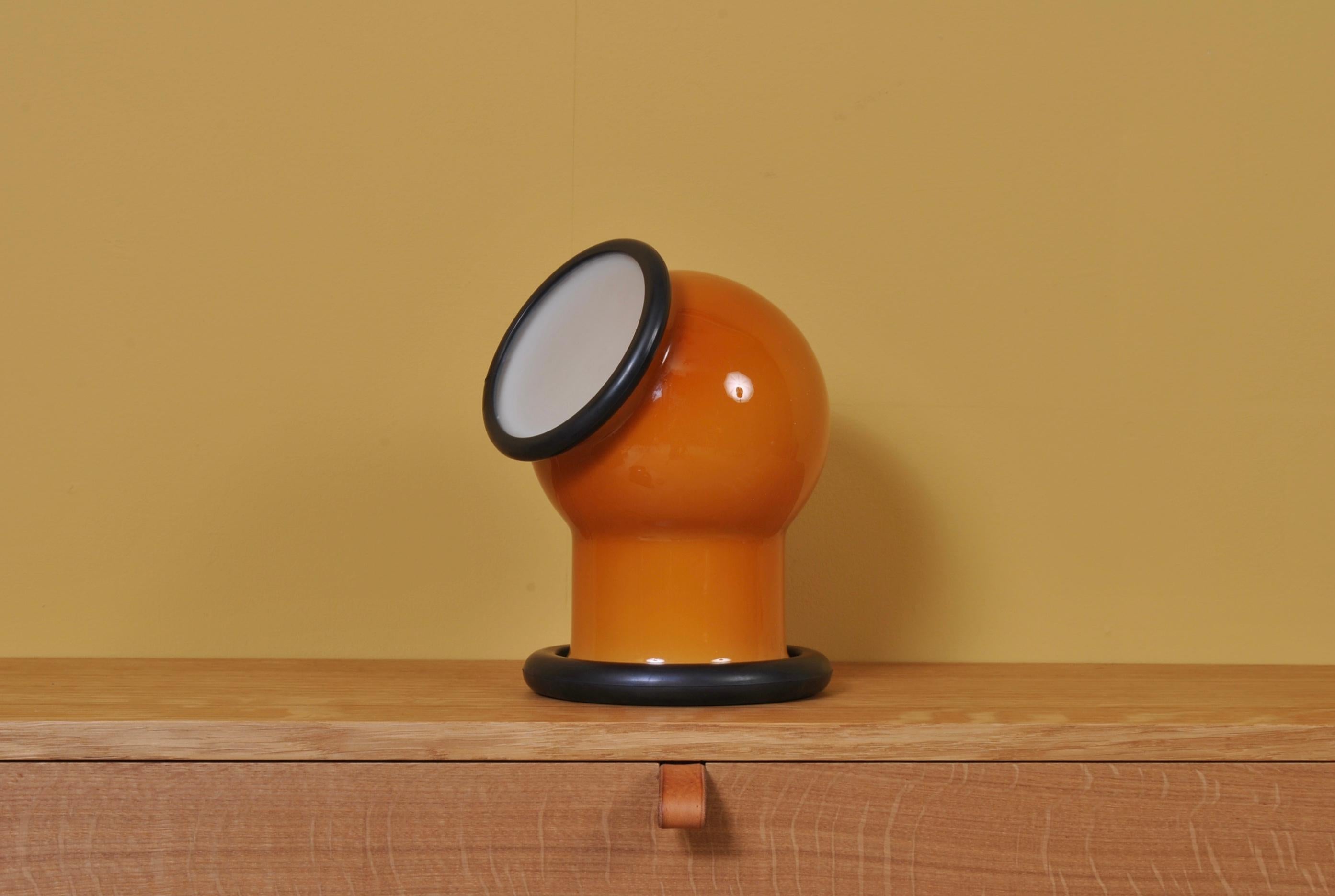 A wonderful midcentury Holmegaard glass Epoke lamp. Designed by Michael Bang for Holmegaard, Denmark, 1972. A playful and characterful design with a slightly nautical nature. Orange main case with white cap. Heavy glass with rubber rim.
Multipurpose